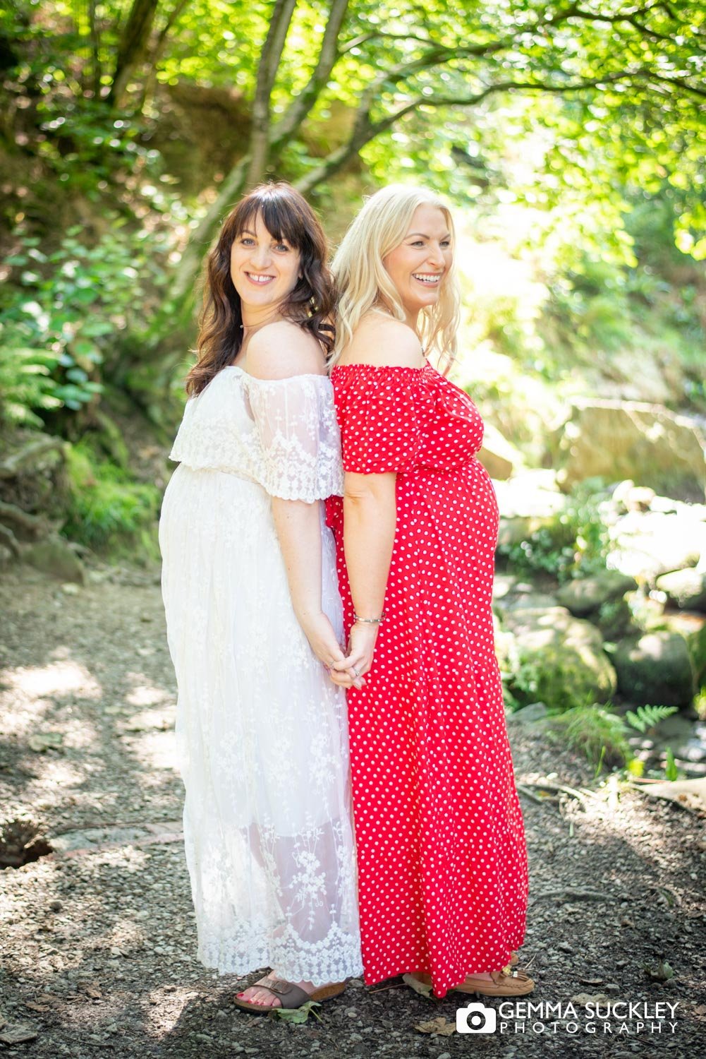 two ladies hold hands on the maternity photoshoot