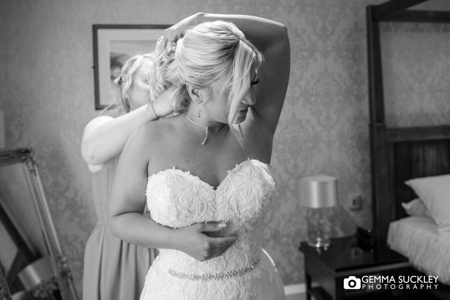 a bridesmaid putting on the brides neckless