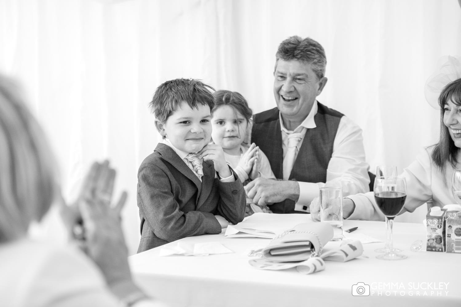 the pageboy smiles as wedding guests clap for him