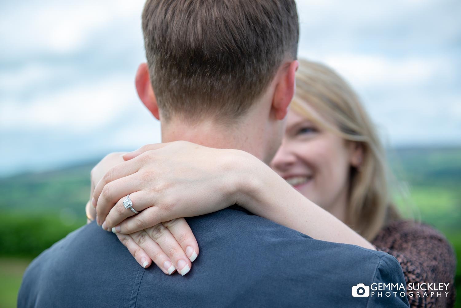 a lady putting her arms around her fiancee's neck showing her engagement ring