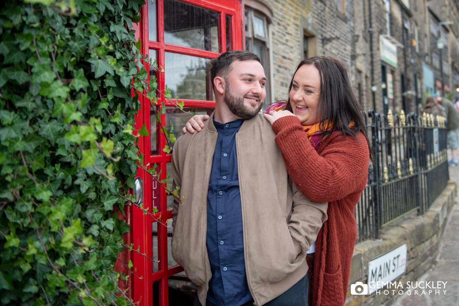 engaged couple next to a red phone box in haworth village