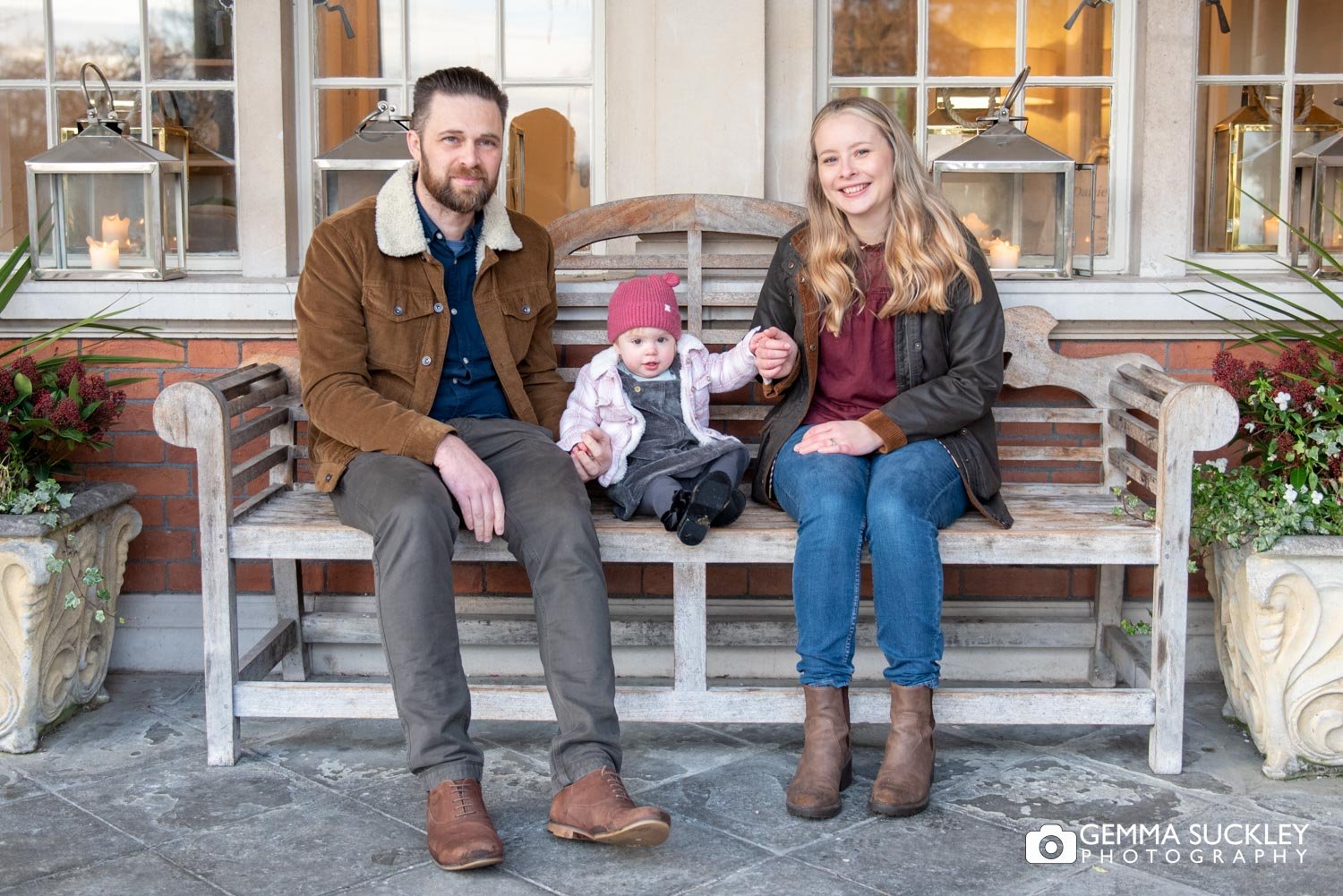 engaged couple and their toddler sitting on a bench outside eaces hall