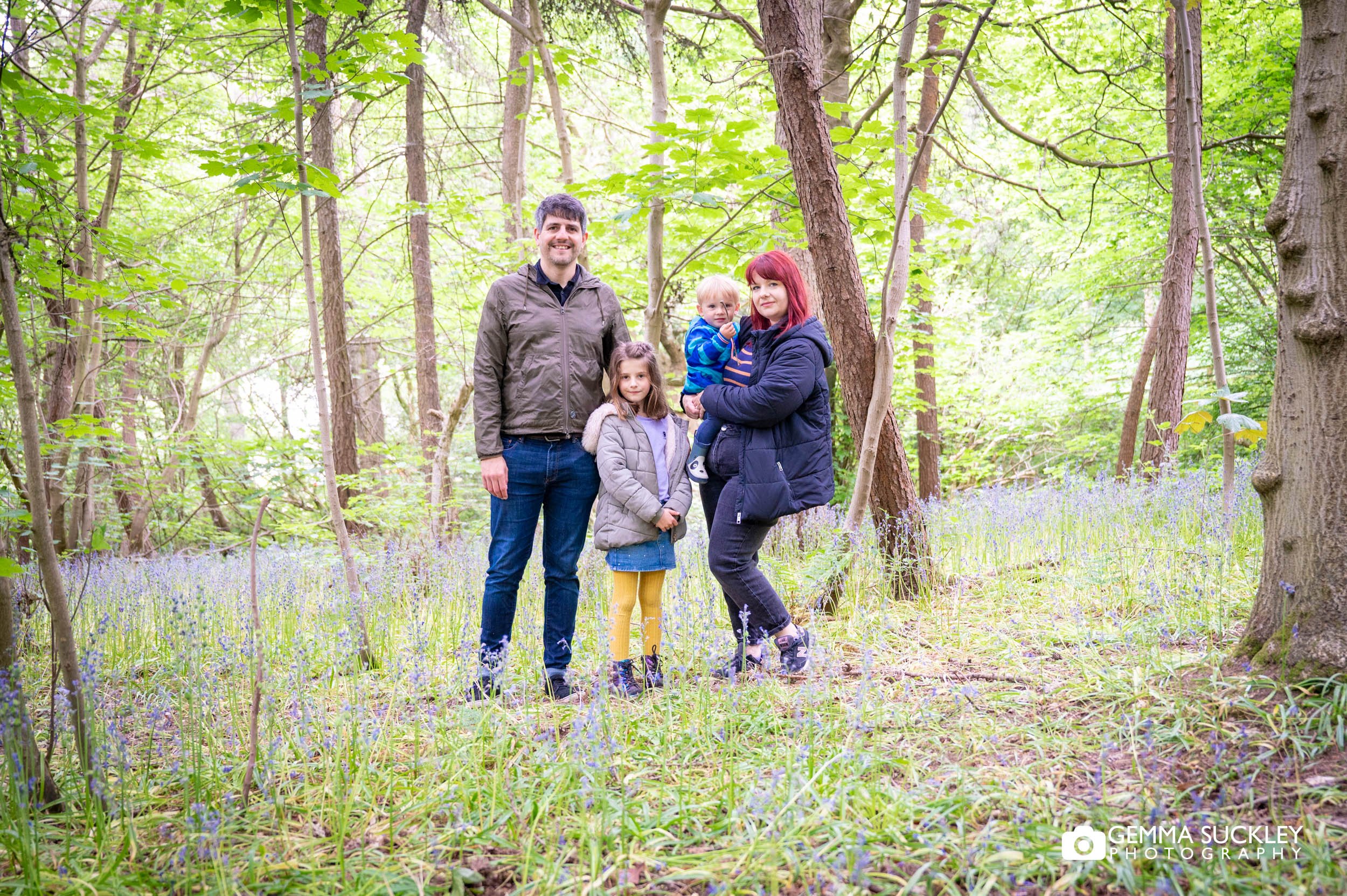 engaged couple with their two children in bluebell woods ilkley