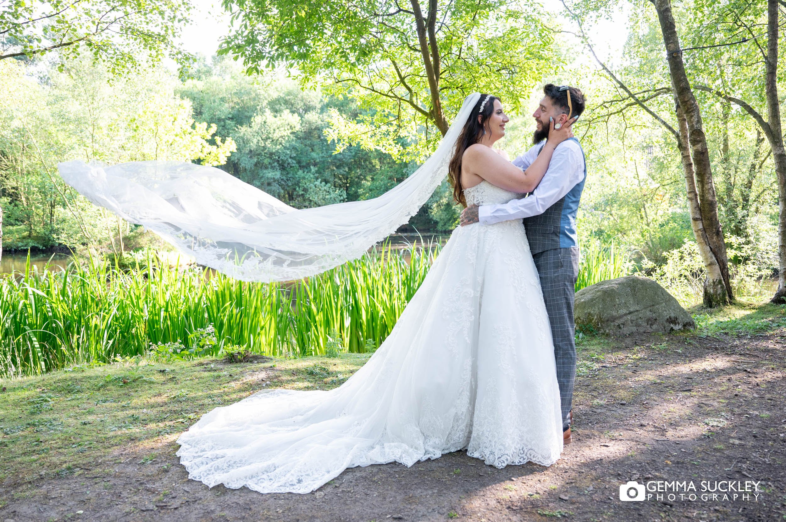 bride and groom hugging as the brides veil blows