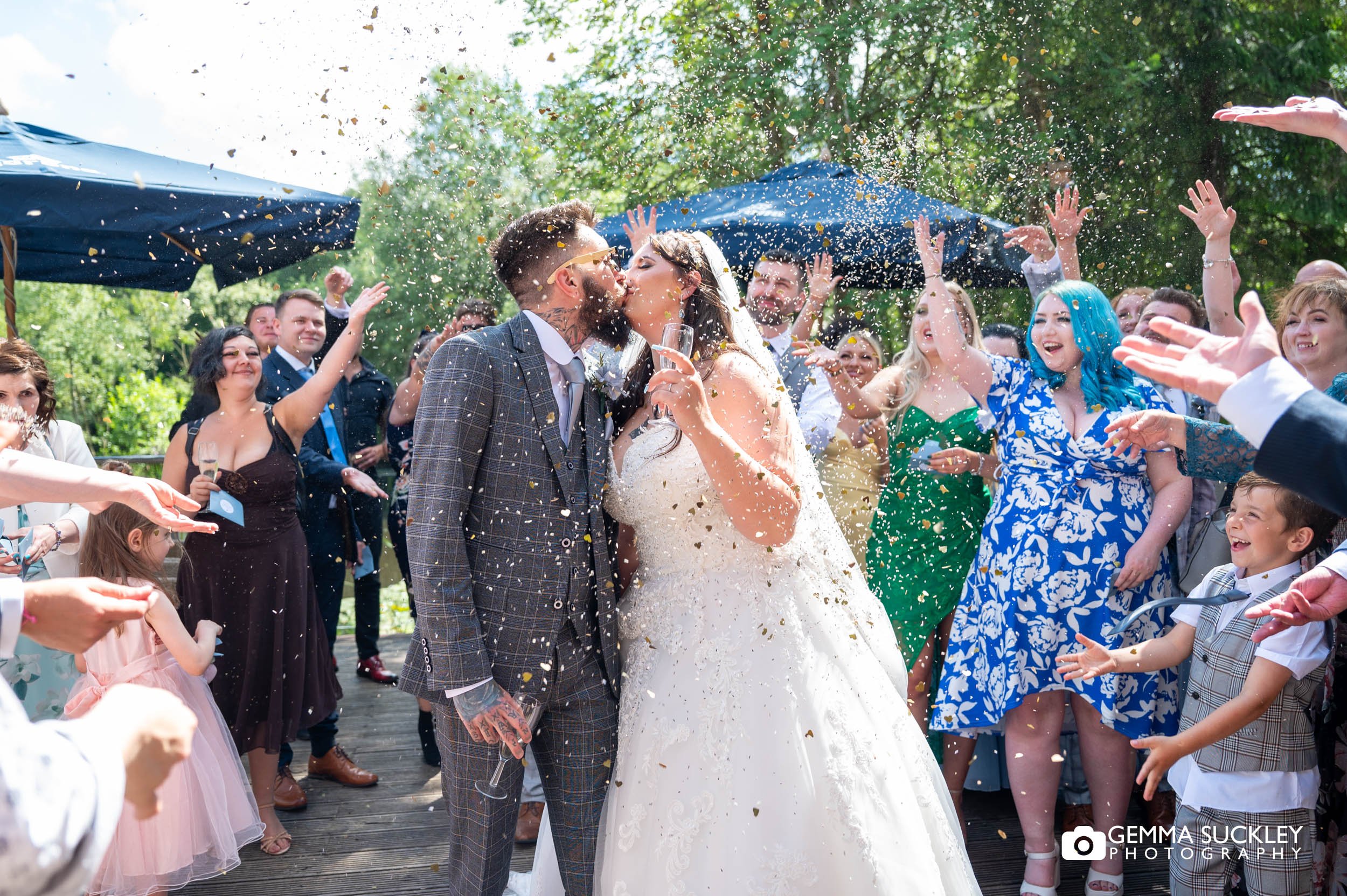 bride and groom kissing as guests throw confetti