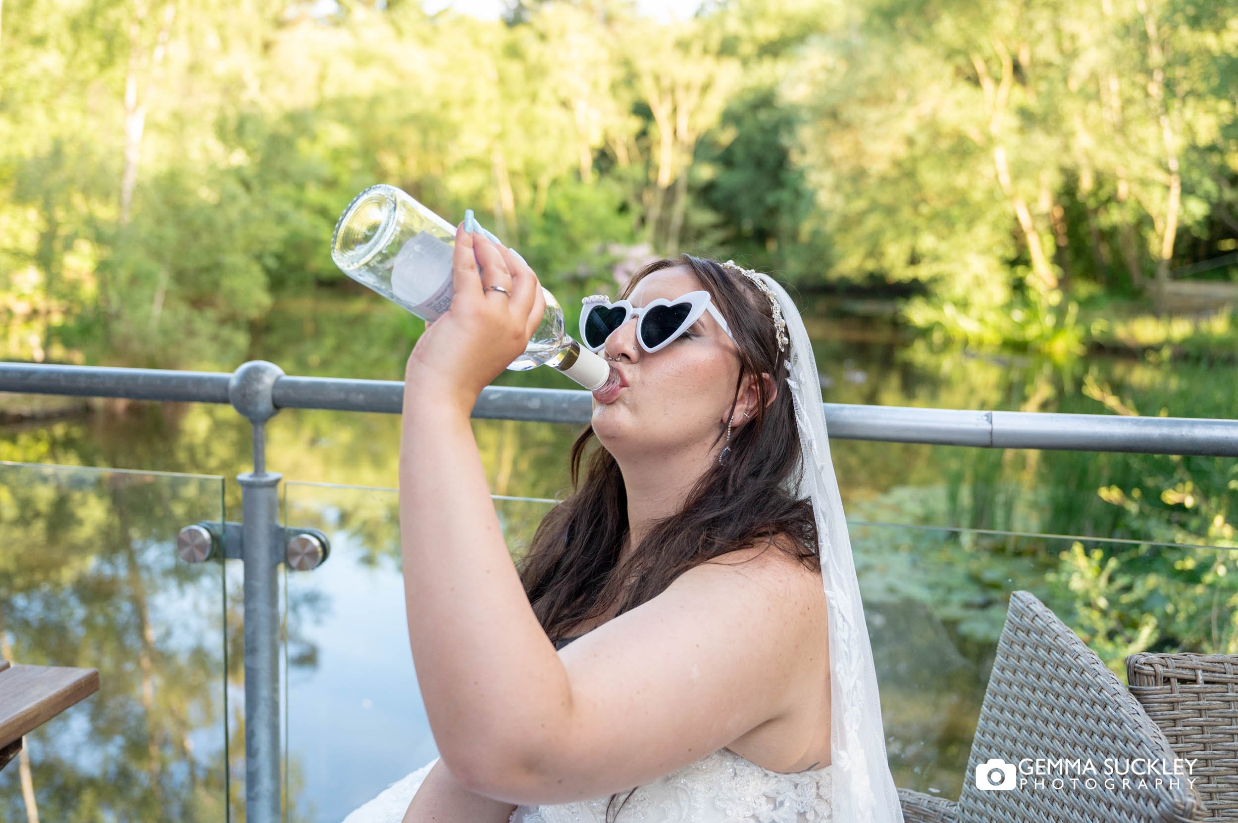 bride in sunglasses drinking wine from the bottle at chevin country park
