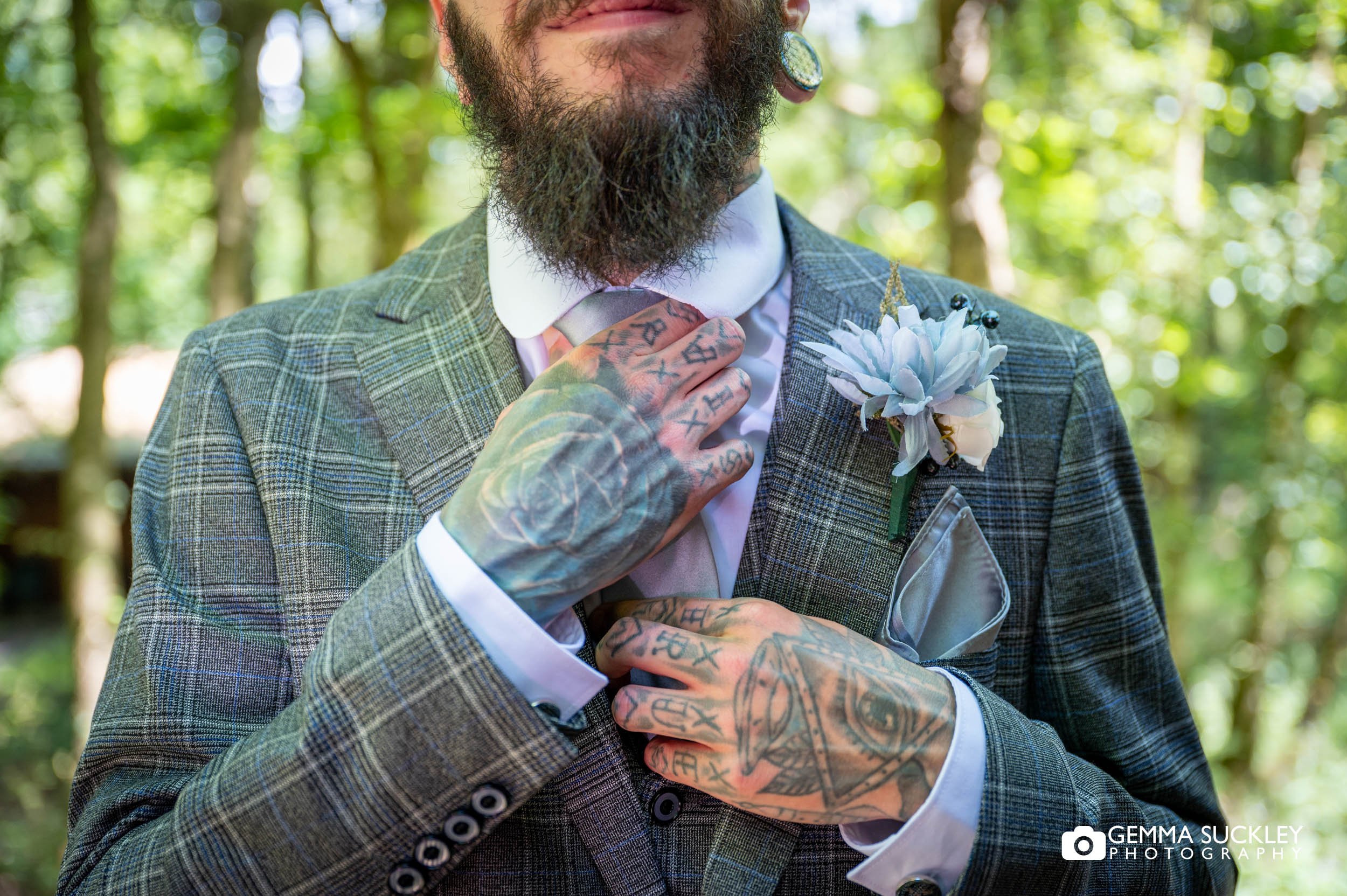 tattooed groom doing up his tie