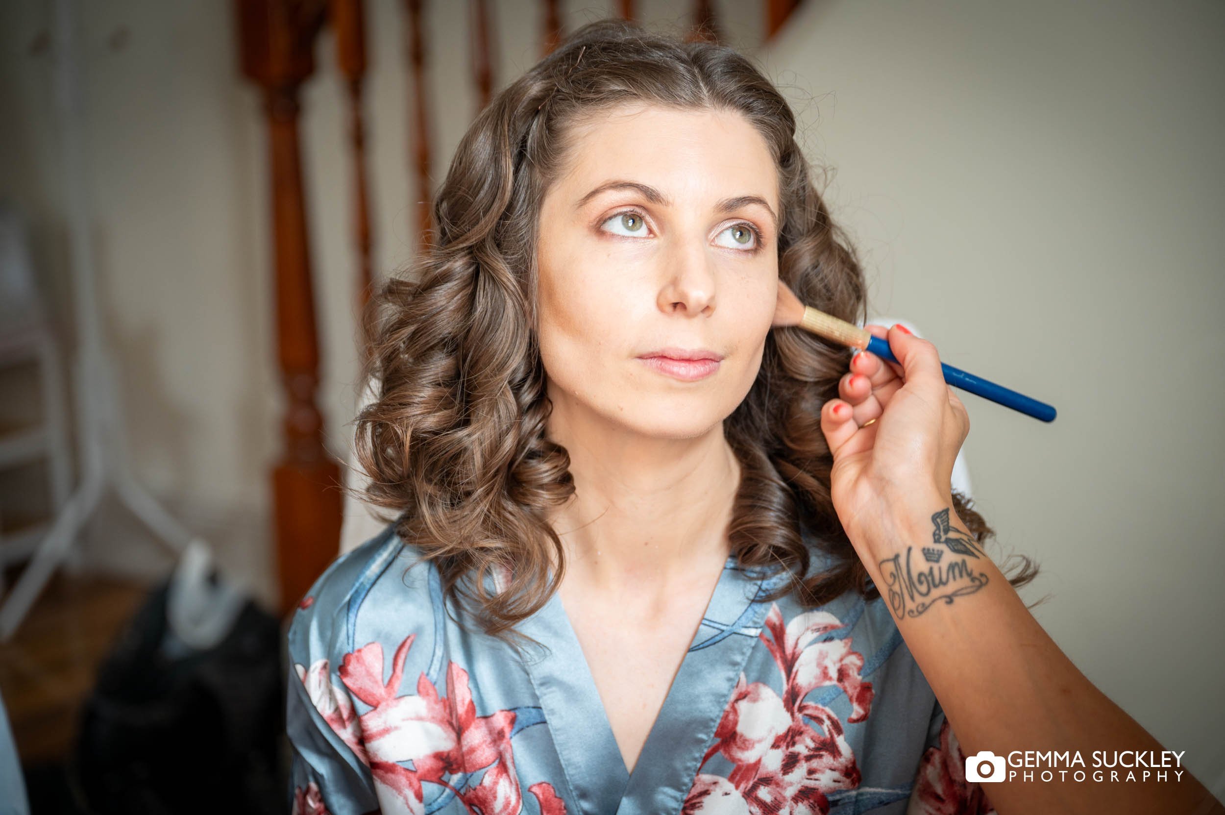 makeup artist applying make up to a bride
