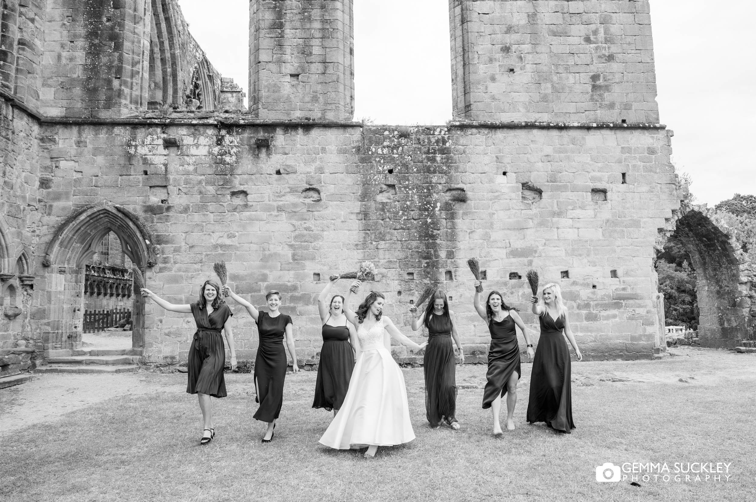 bridesmaids waving their flowers above their heads at bolton abbey
