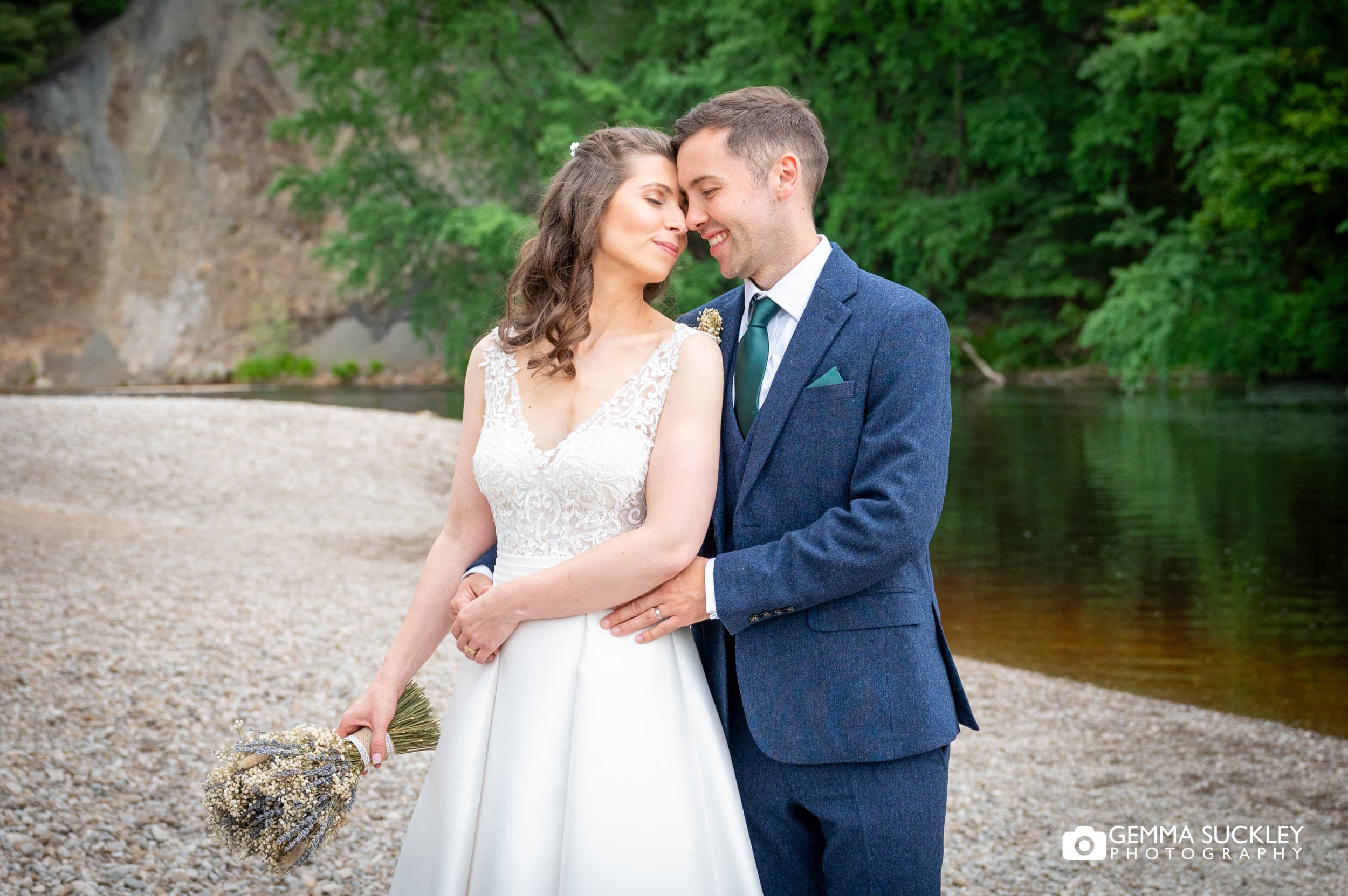 the bride and groom hugging a bolton abbey river