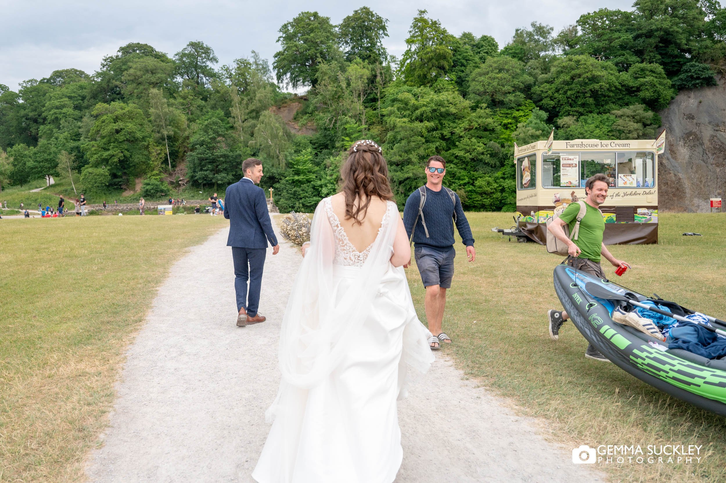 bride and groom walking as canoer pass at bolton abbey