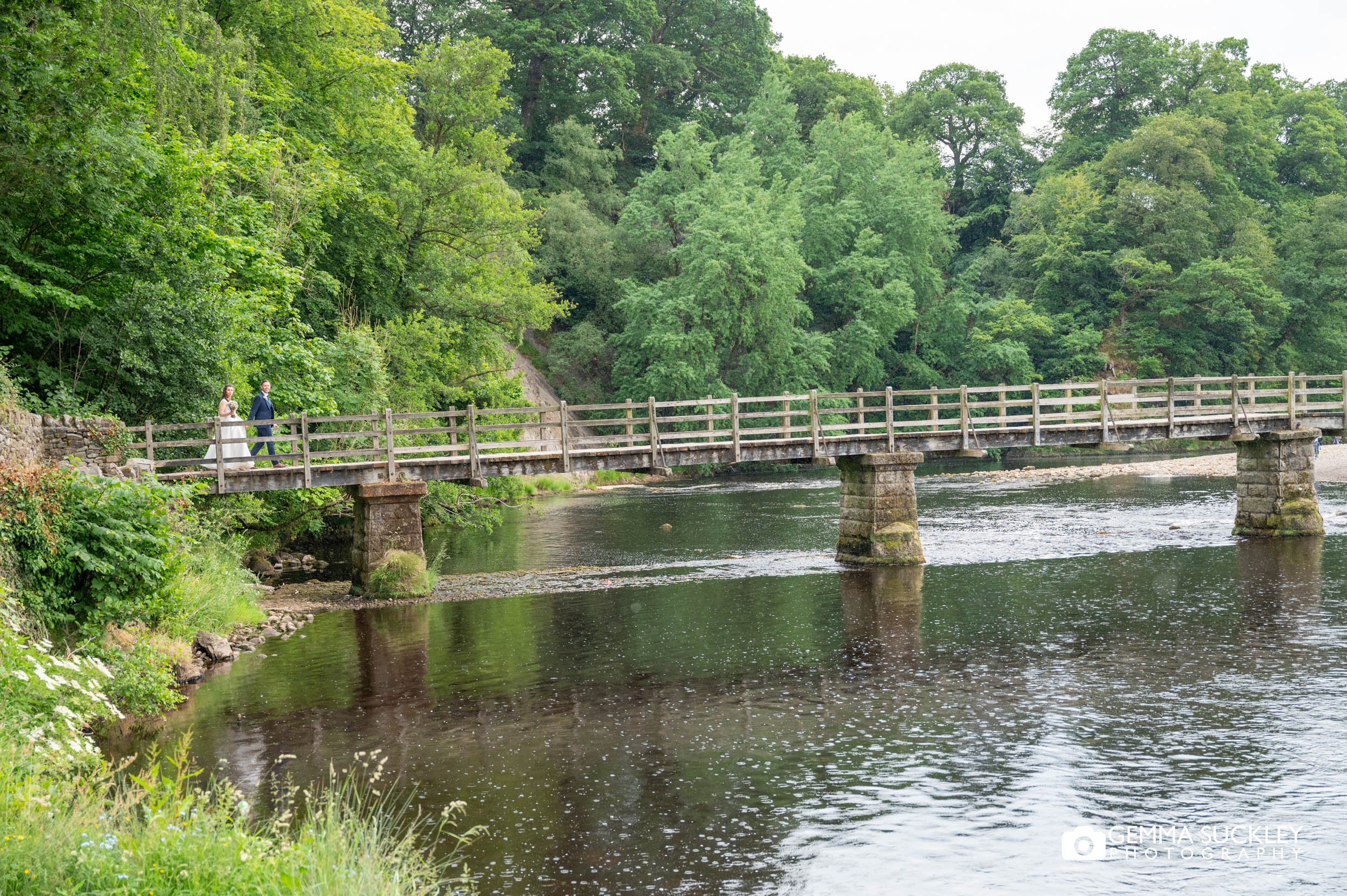 bride and groom walking over the bridge at bolton abbey