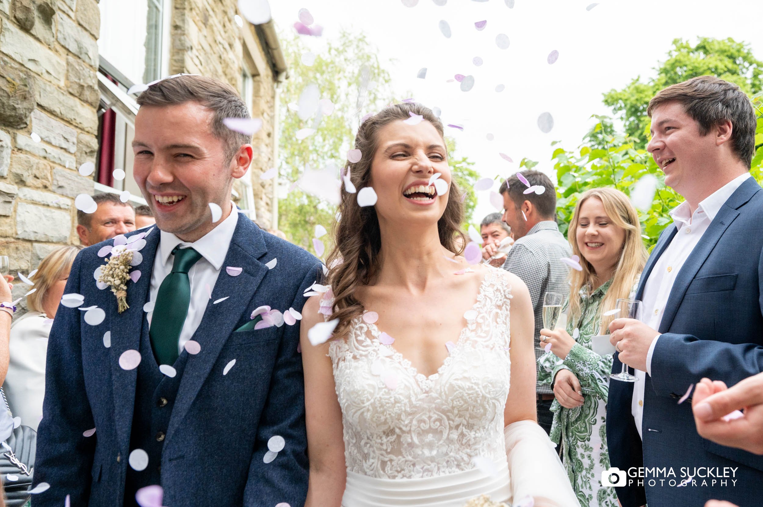 bride and groom laugh as guests throw confetti