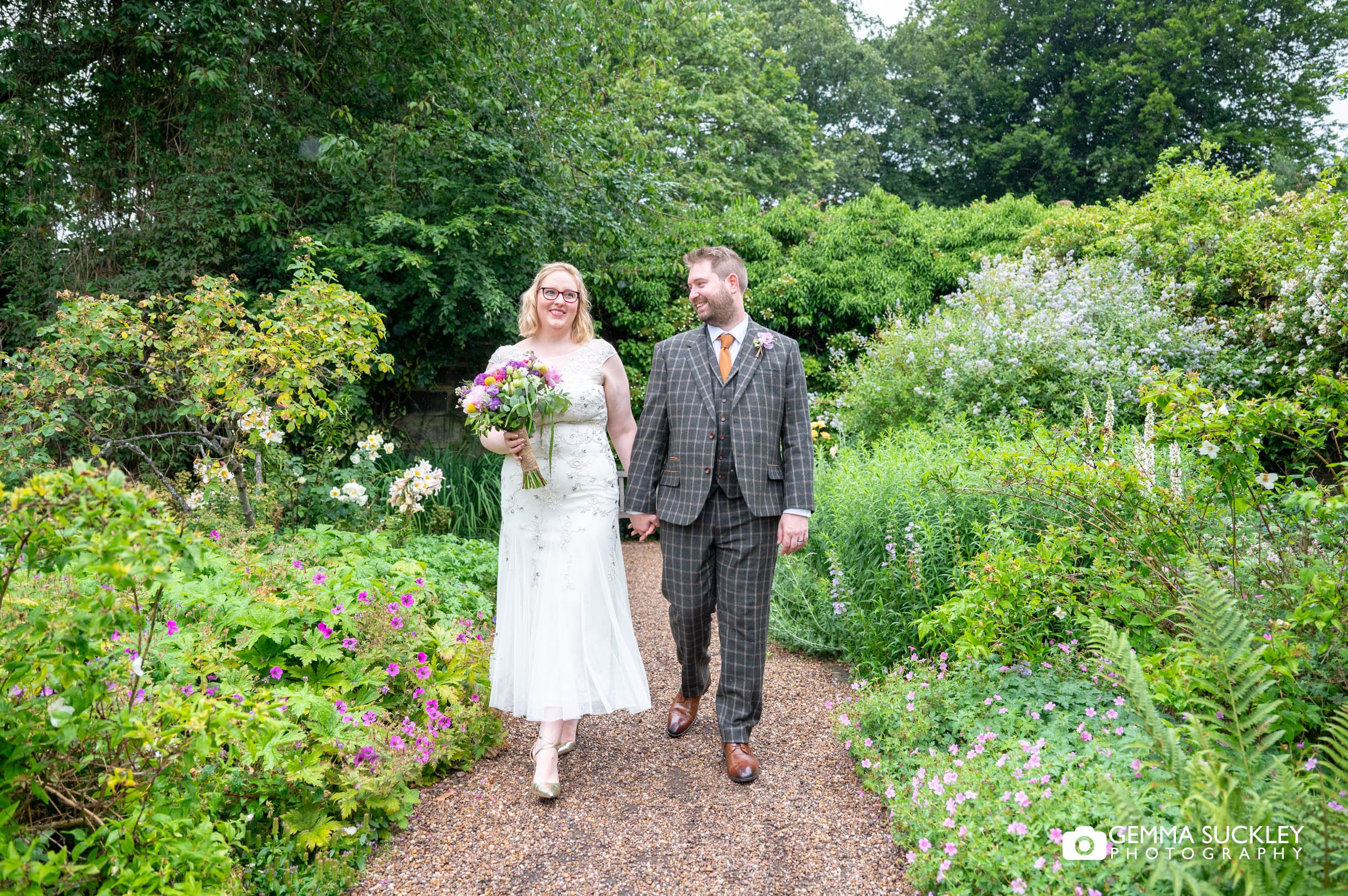 just married couple walking in the garden at east riddlesden hall