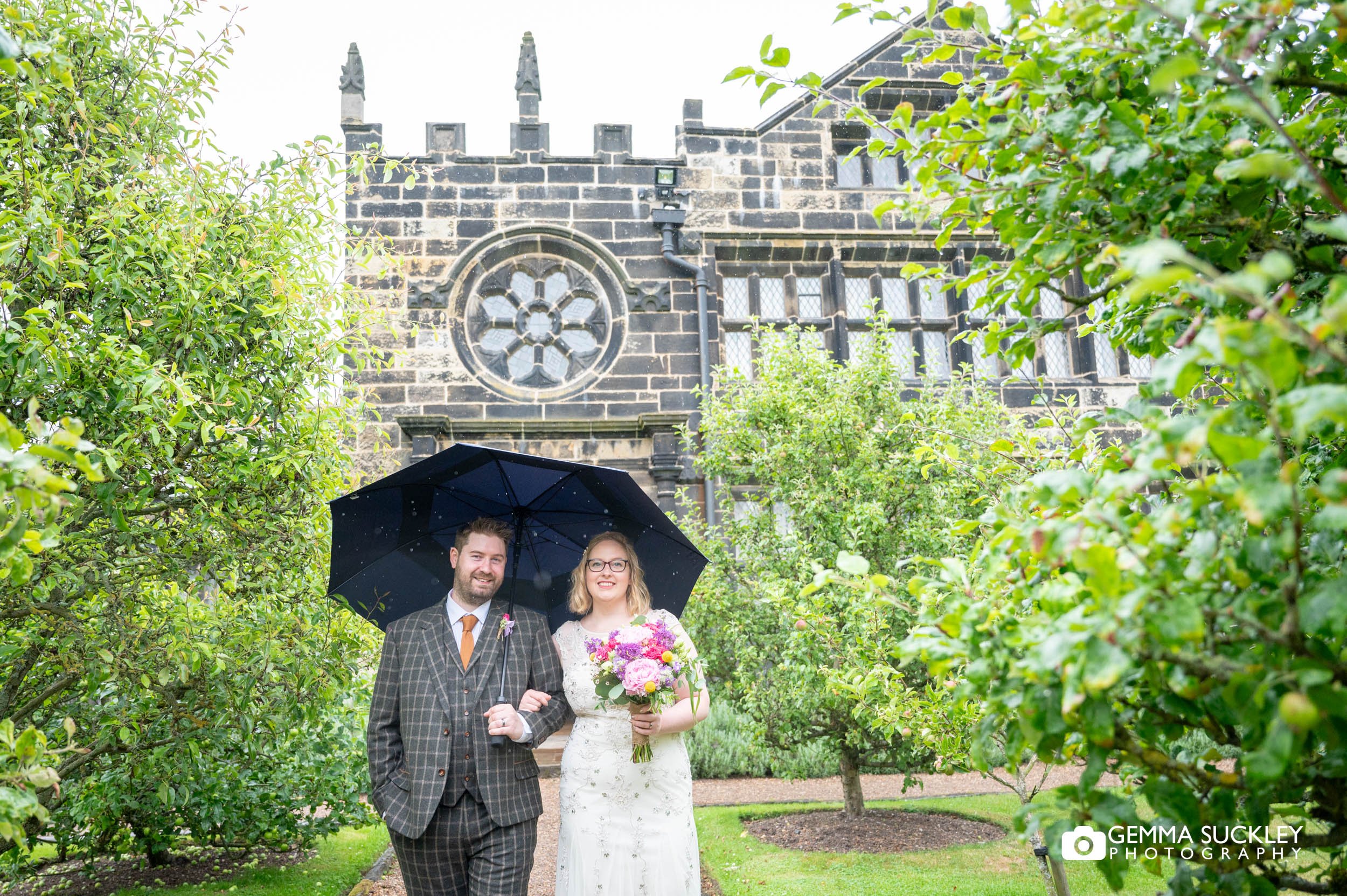 marride couple walking in the rain at east riddlesden hall wedding