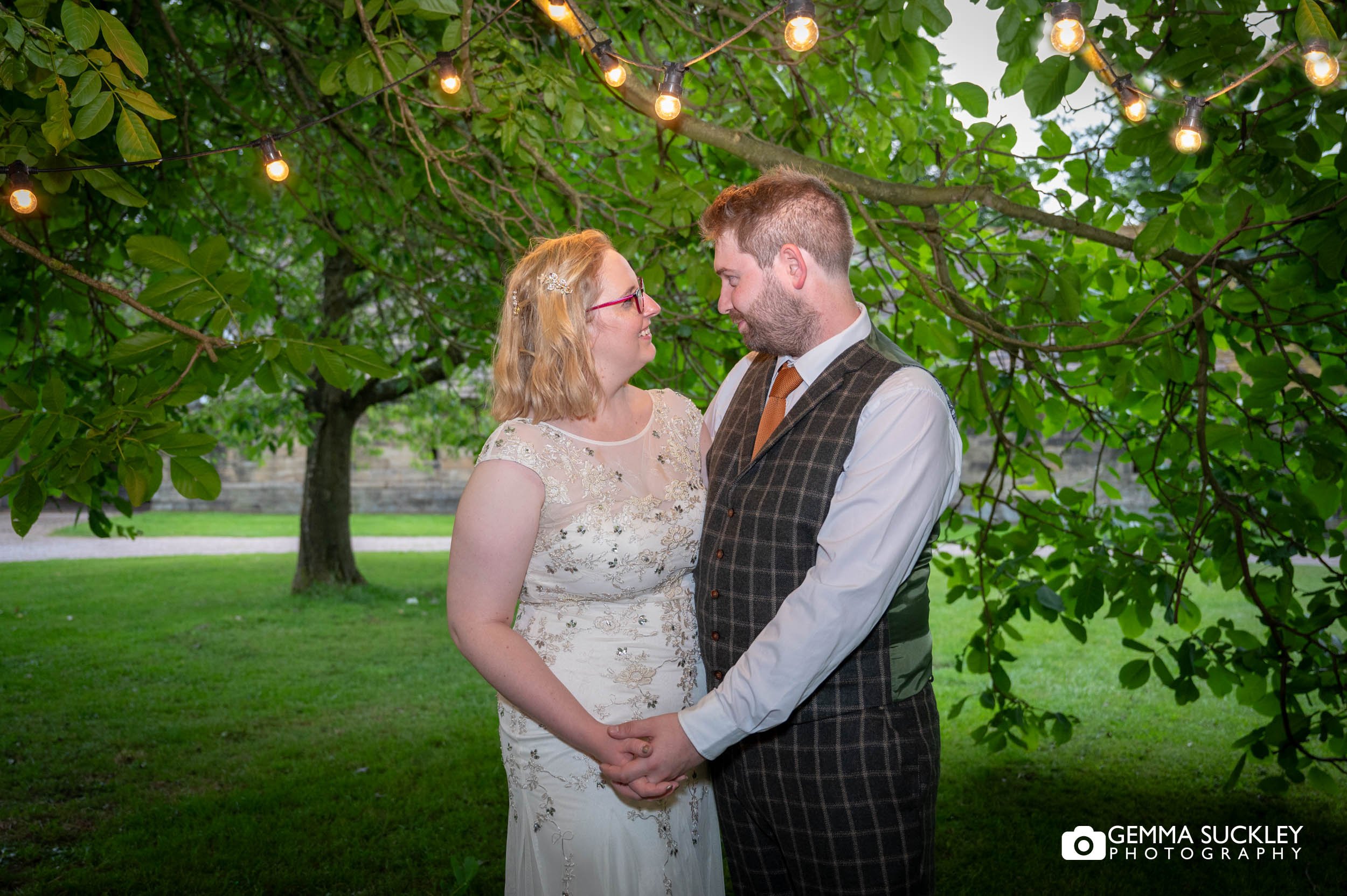 married couple under the fairly lights at east riddlesden hall