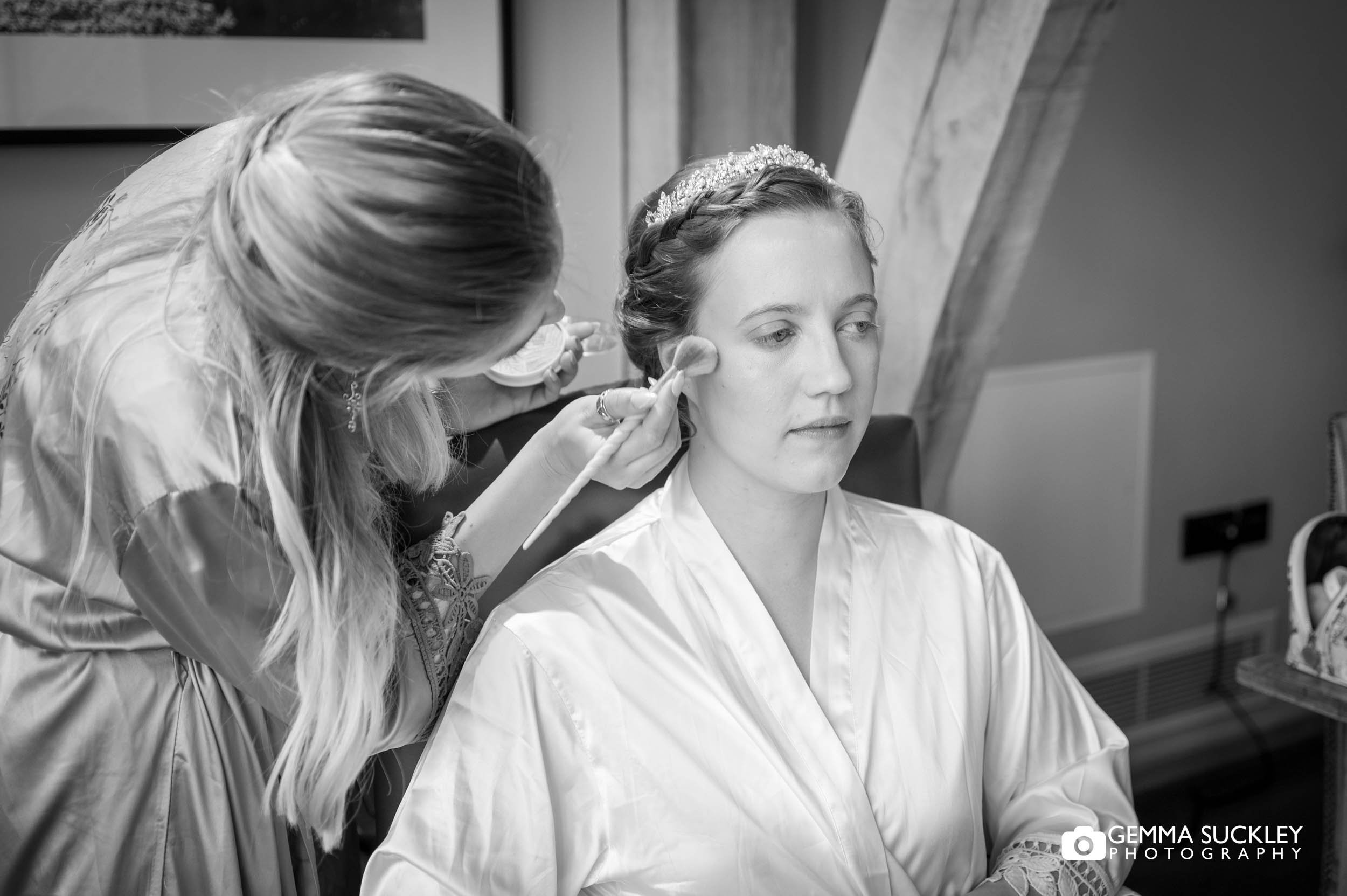 bridesmaid applying makeup to the bride