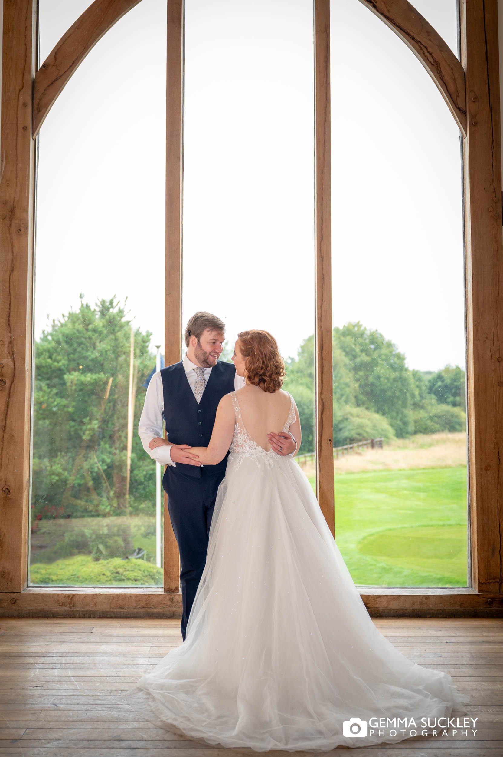 bride and groom in front of the window at sandburn hall