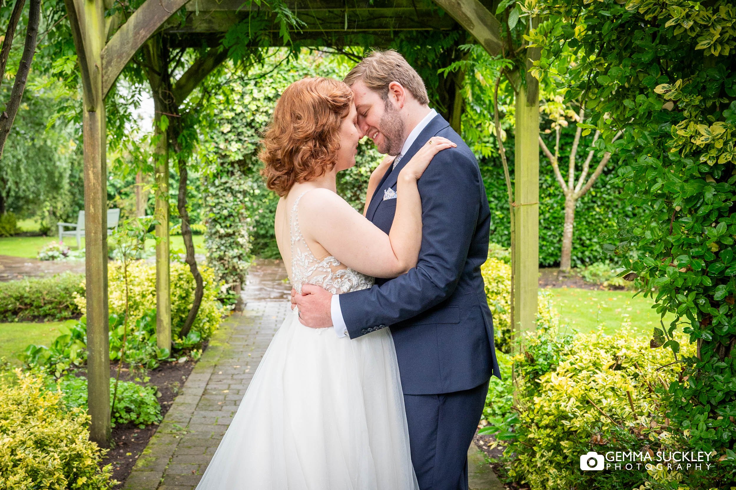 newly-weds hugging in the rise garden at sandburn hall