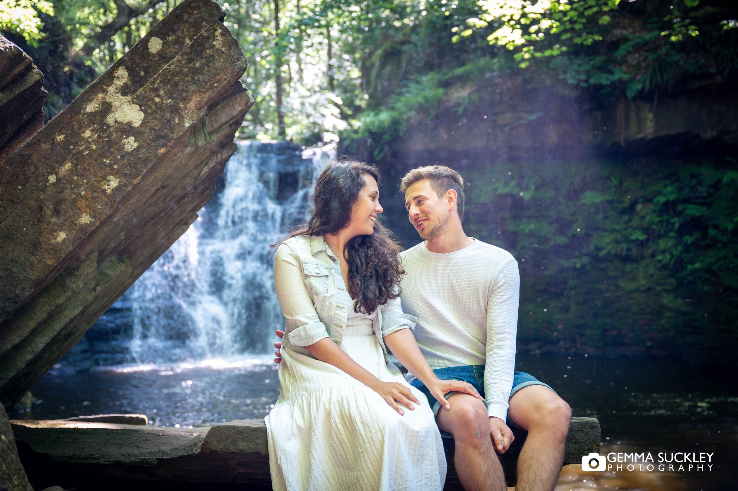 couple sitting in front of goitstock waterfall
