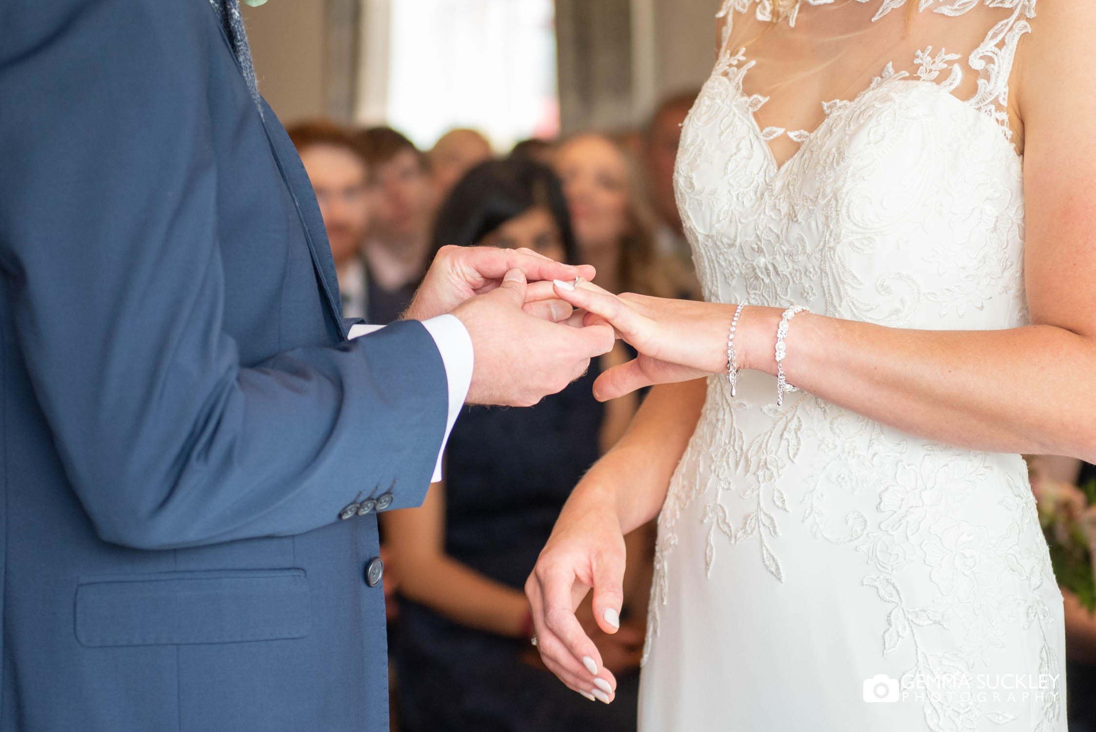 groom putting the ring on his brides finger