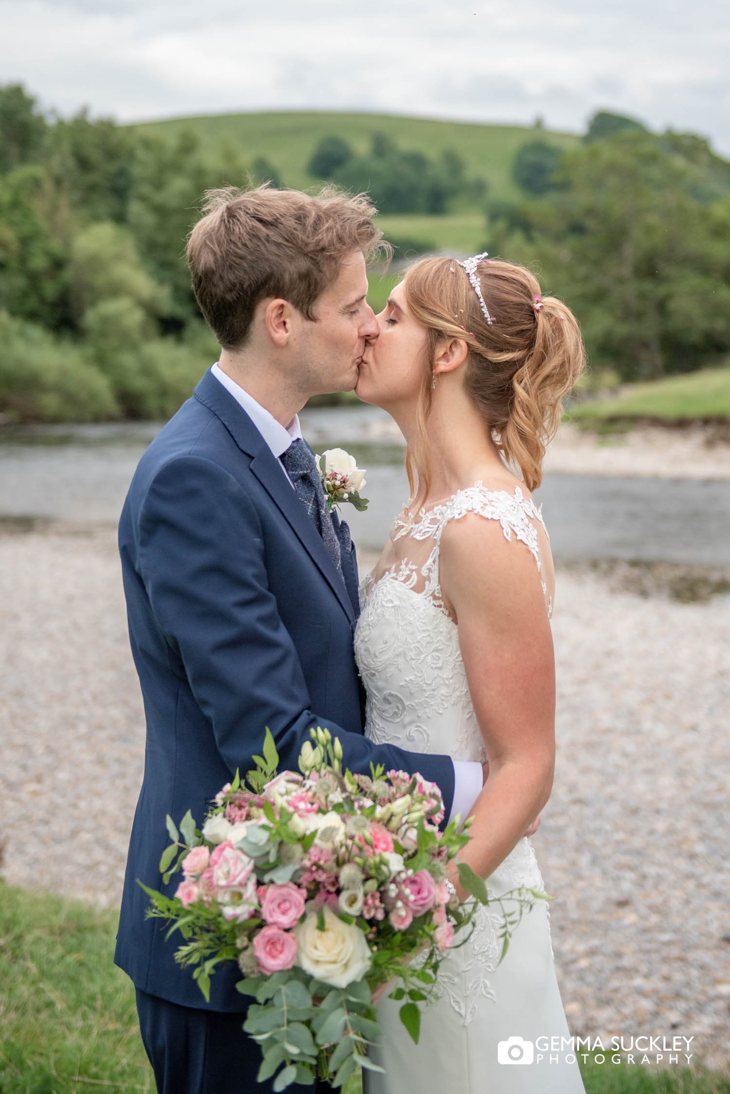 just married couple kissing at burnsall river