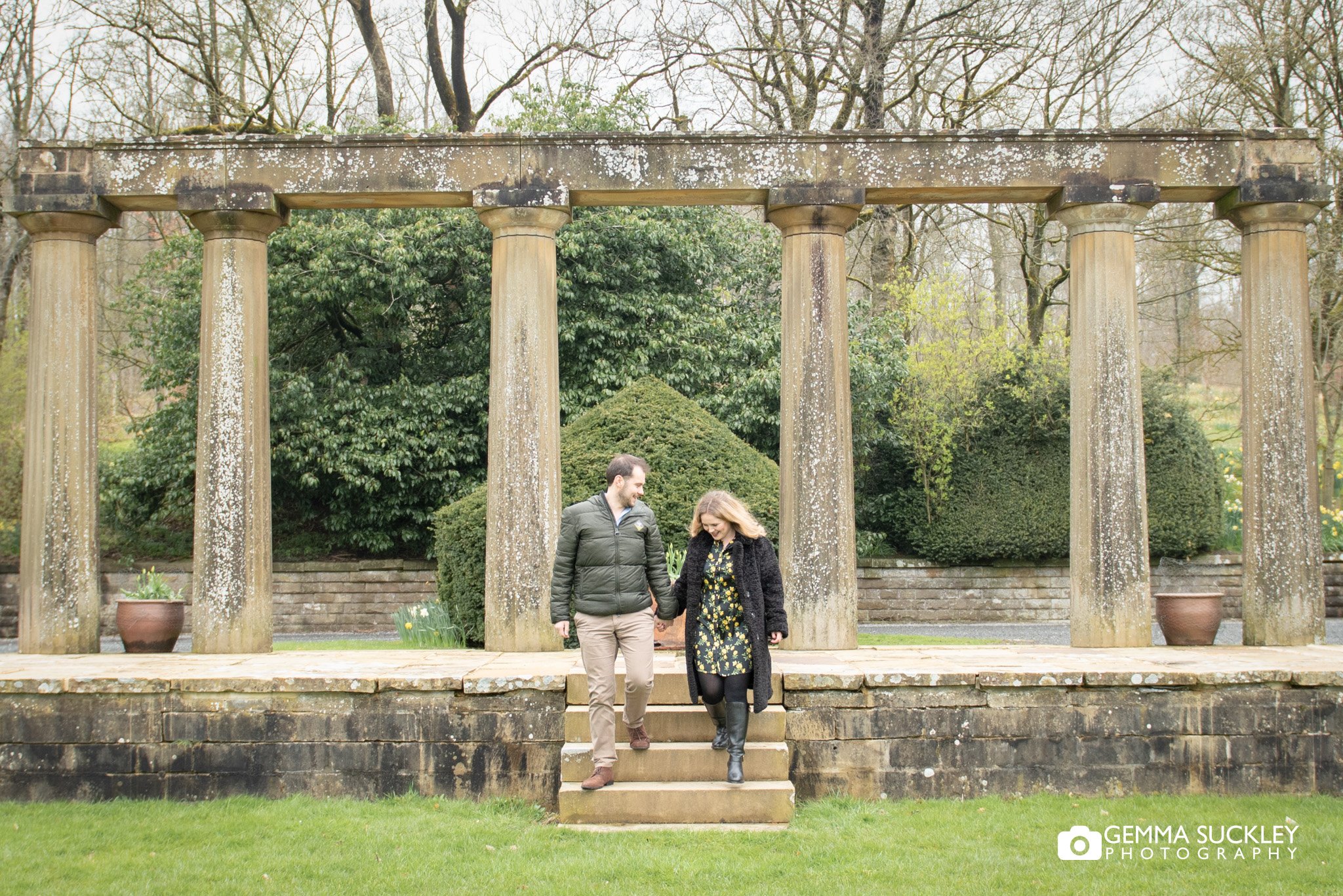 engaged couple walking by the ruin at coniston hotel estate