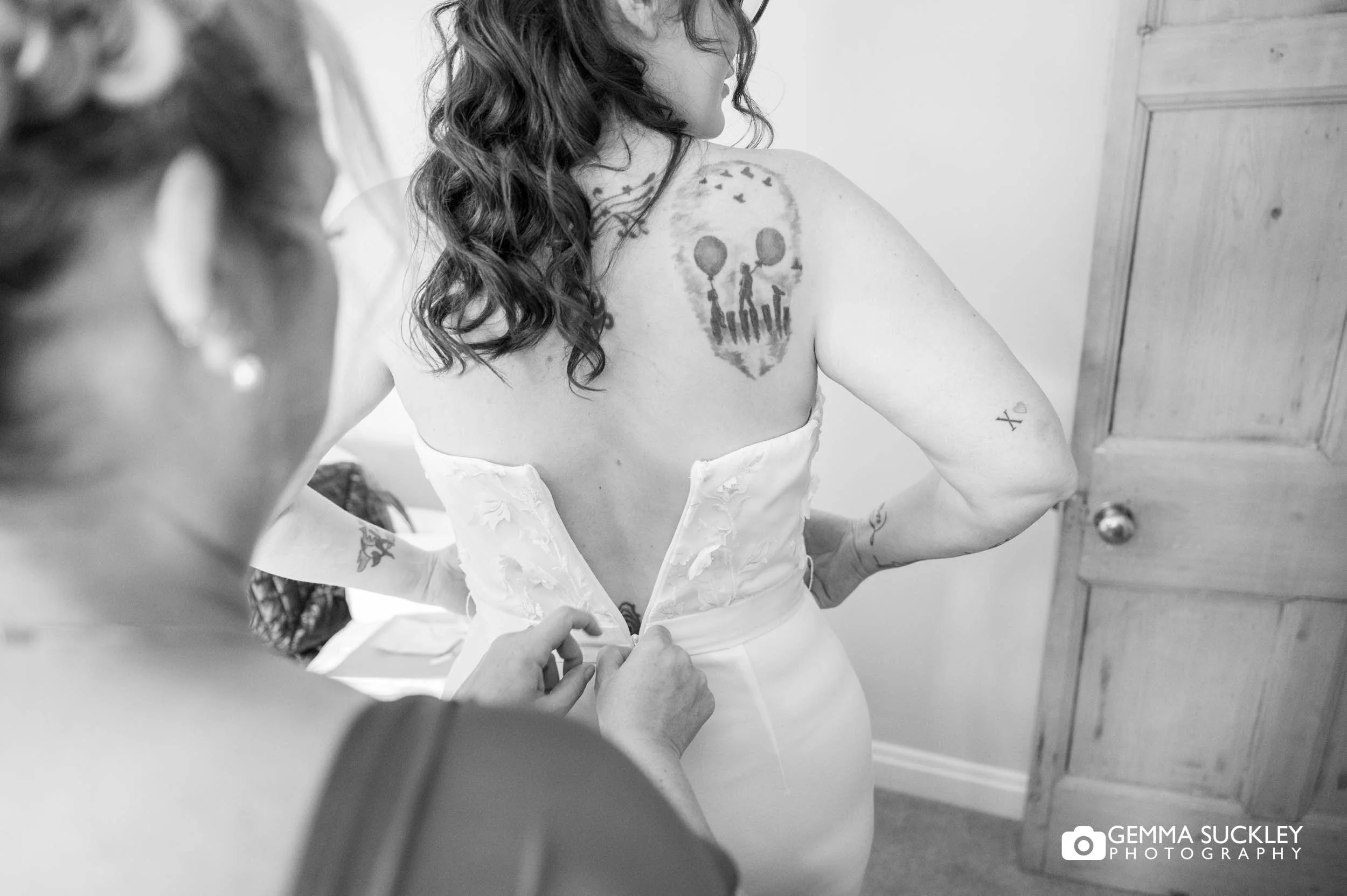 bridesmaid help the brides with her dress