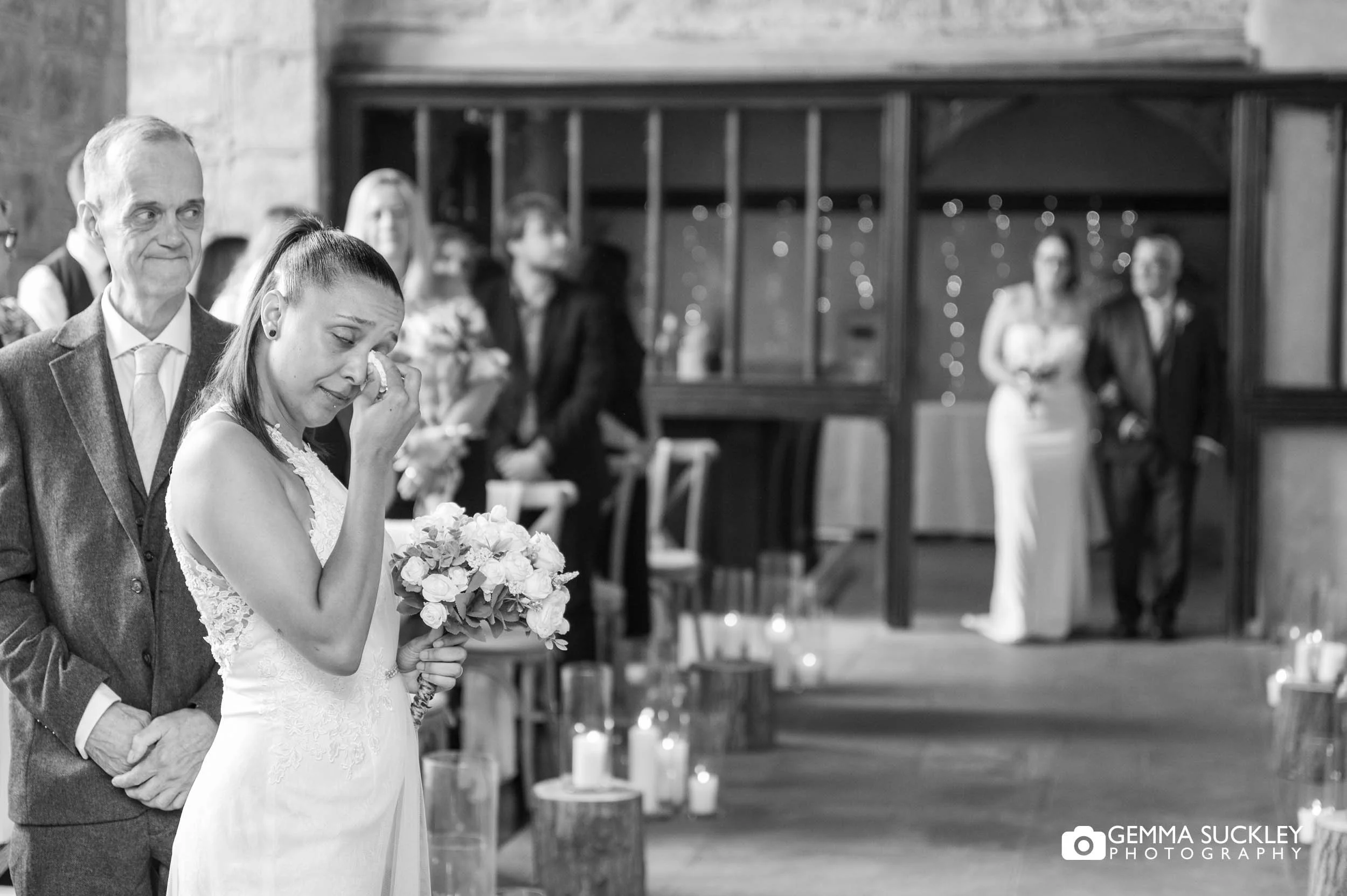 bride crying as her bride walks down the aisle