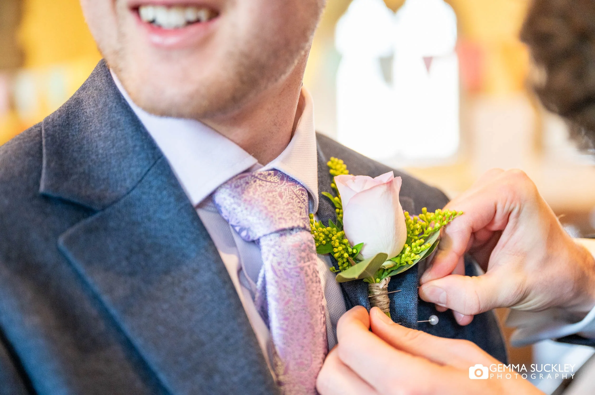 the best man putting on the grooms button hole