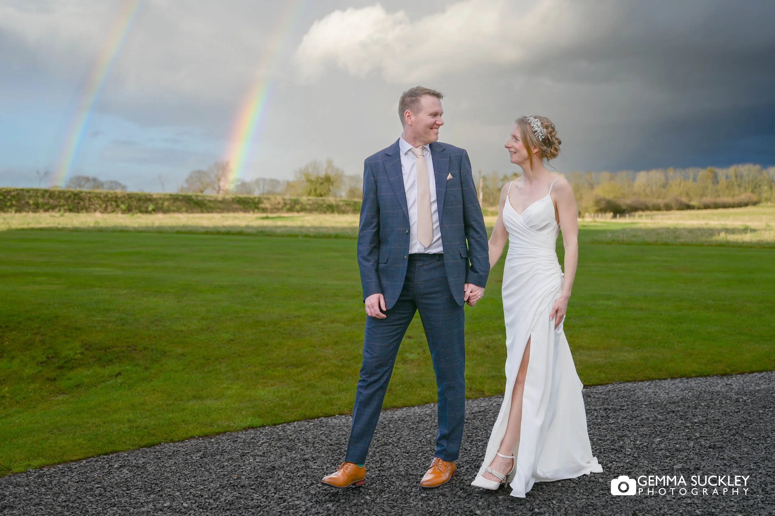 married couple walking in front of a double rainbow at thirsk lodge barns