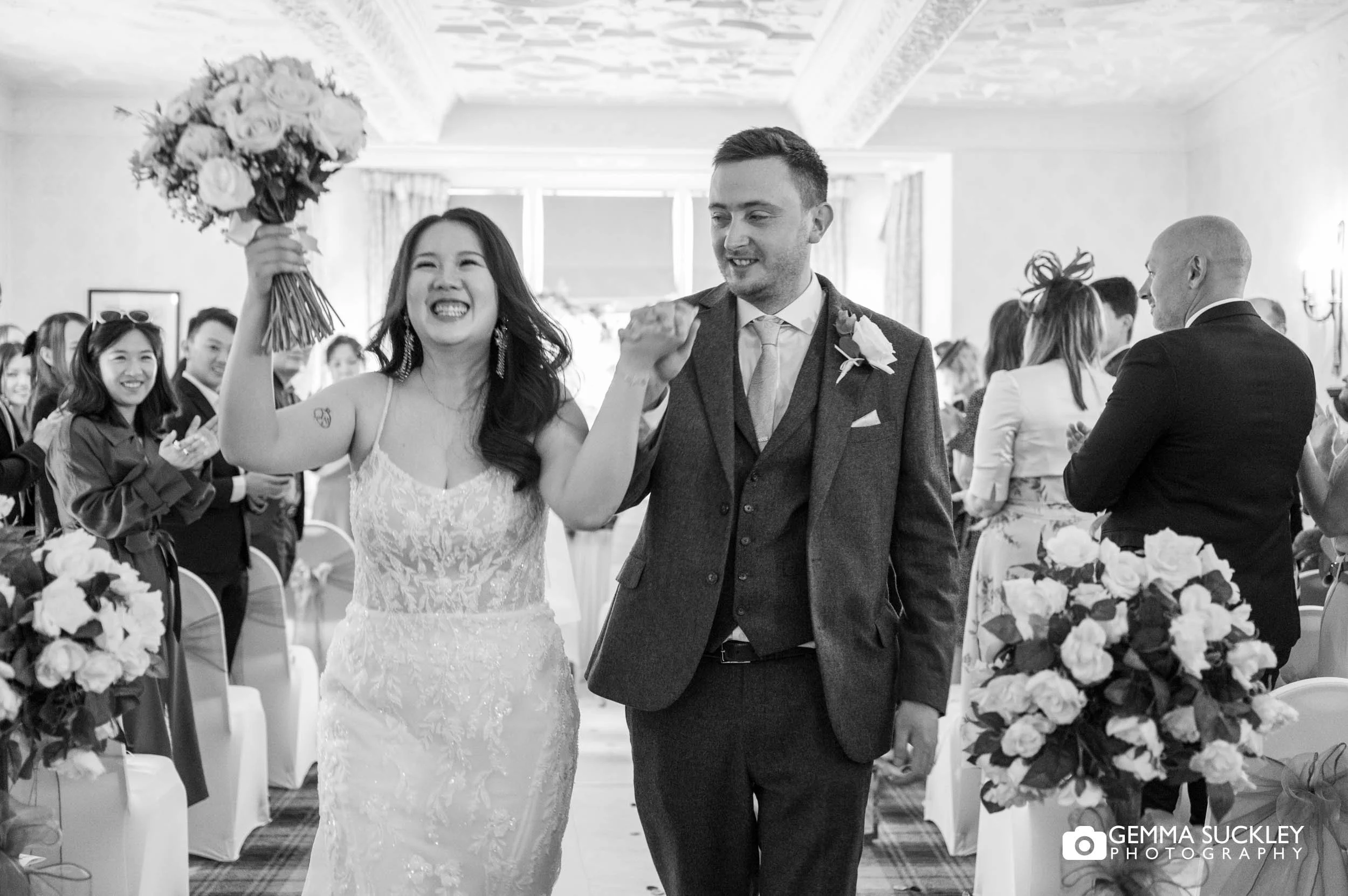 bride laughing and raising her bouquet as they exit the ceremony room 