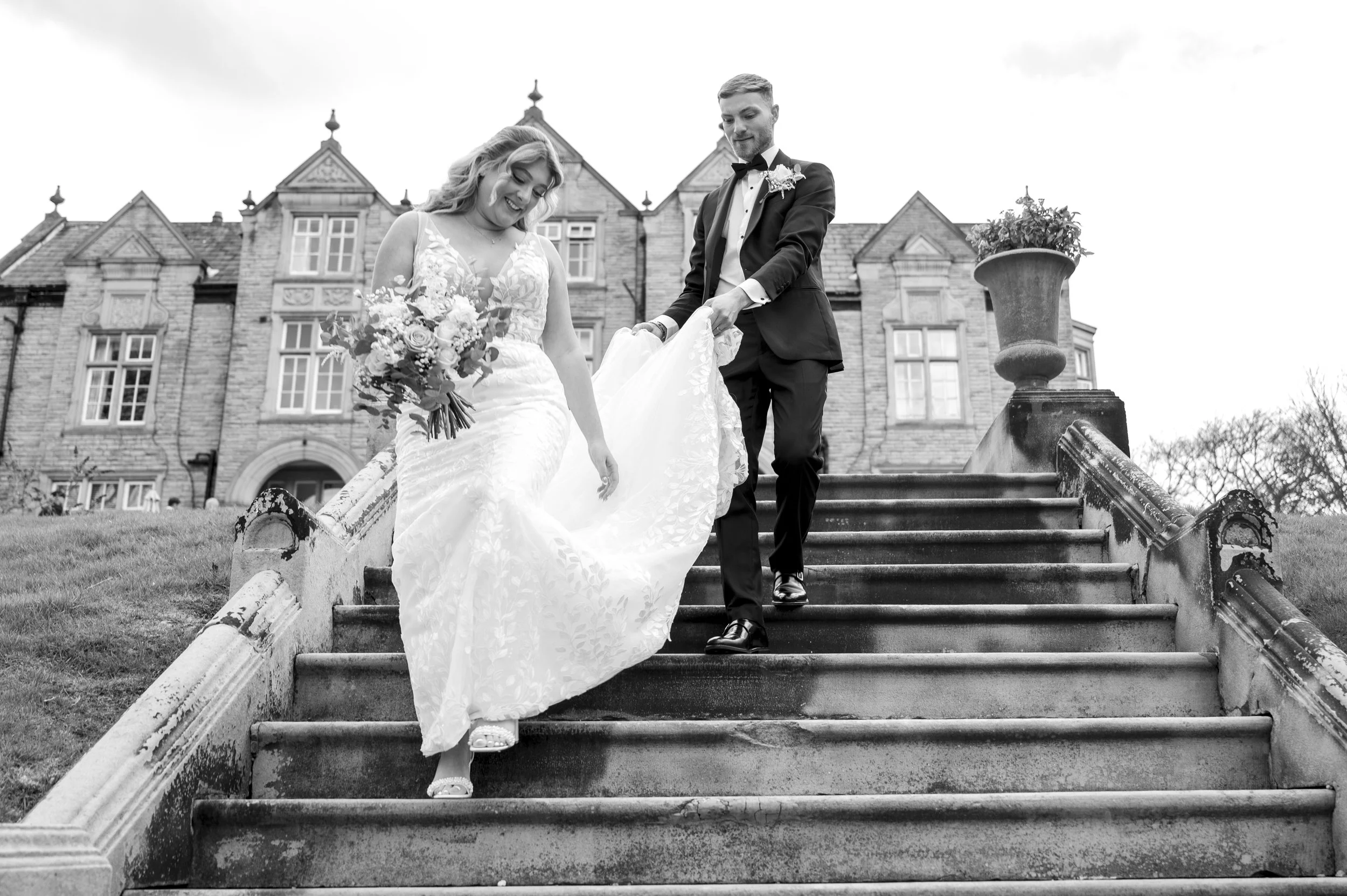 groom helping with his brides dress in the garden at woodland hotel in leeds