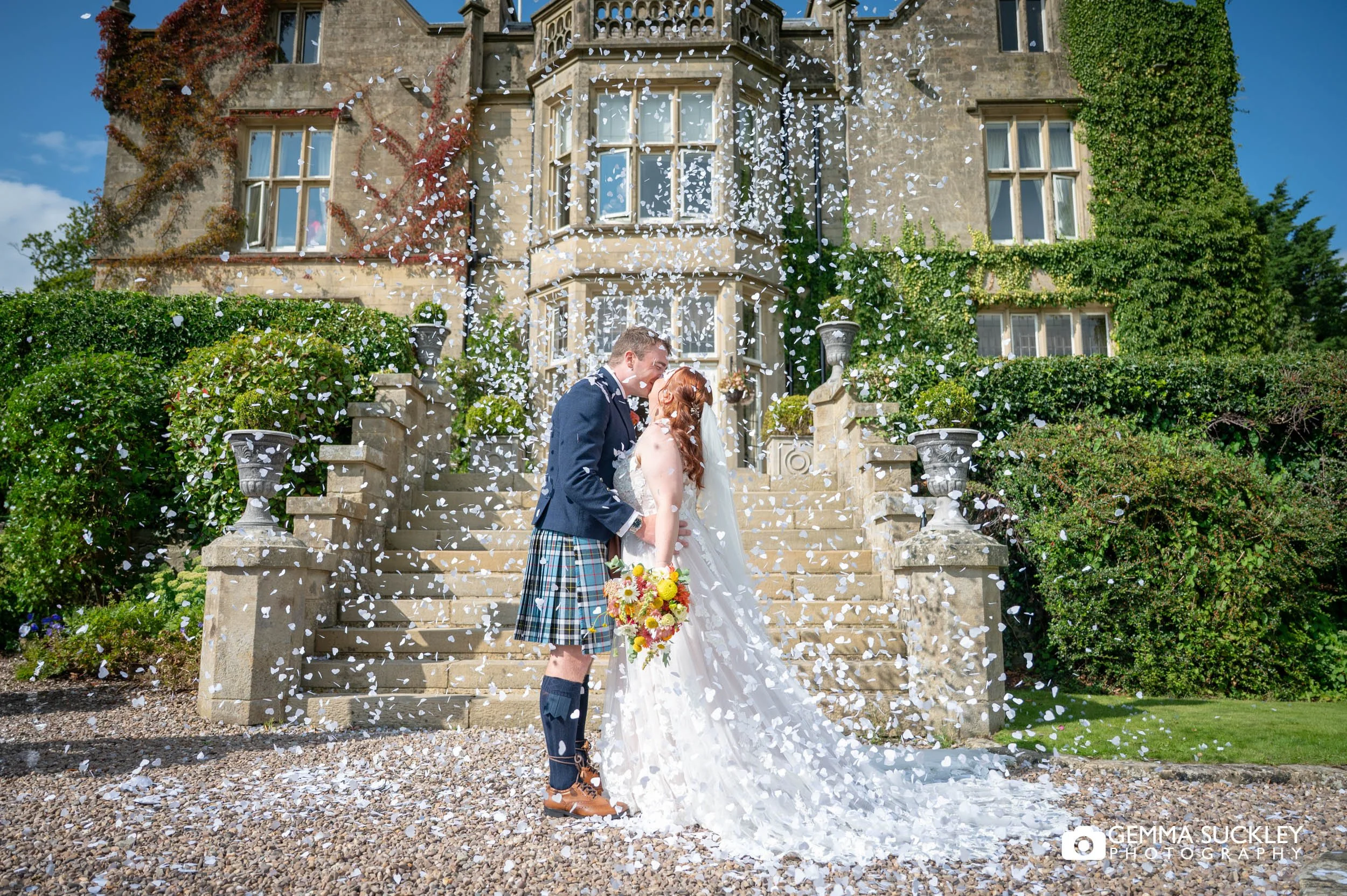 married couple kiss at confetti falls in front of the falcon manor