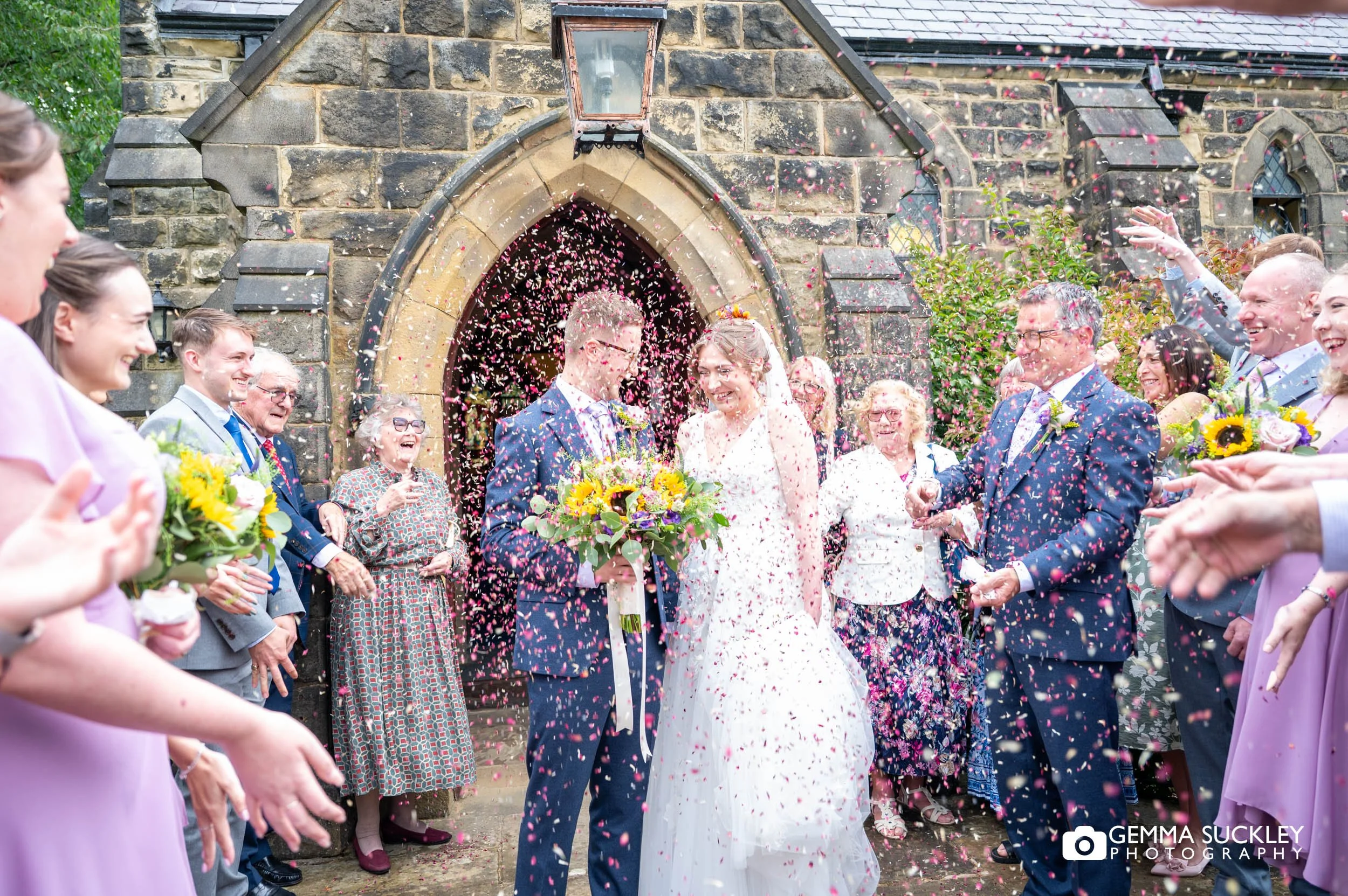 wedding guests throwing confetti at the bride and groom 