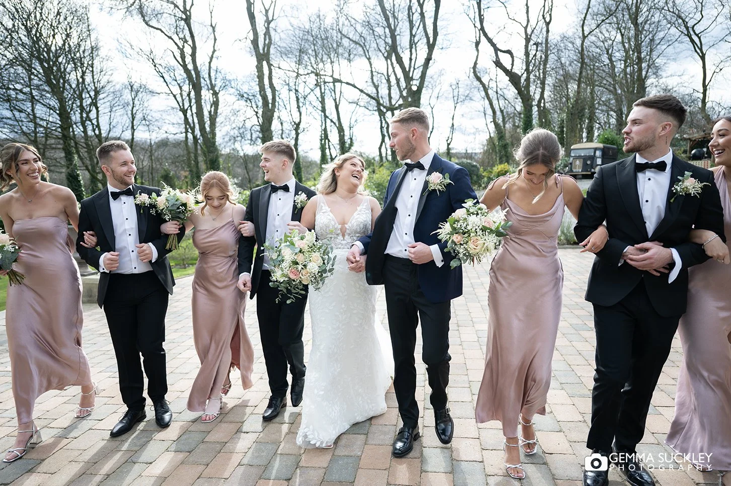 bridal and grooms party walk arm in arm at woodland hotel wedding