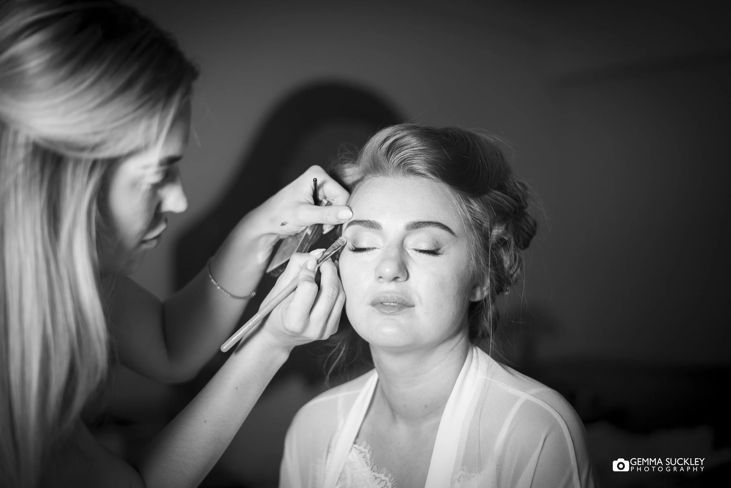 makeup artist applying makeup to the bride at nunsmere hall