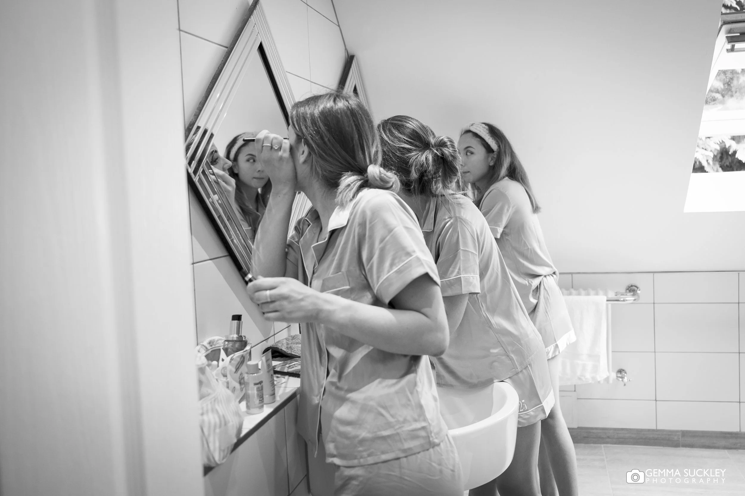 a line of bridesmaids applying makeup