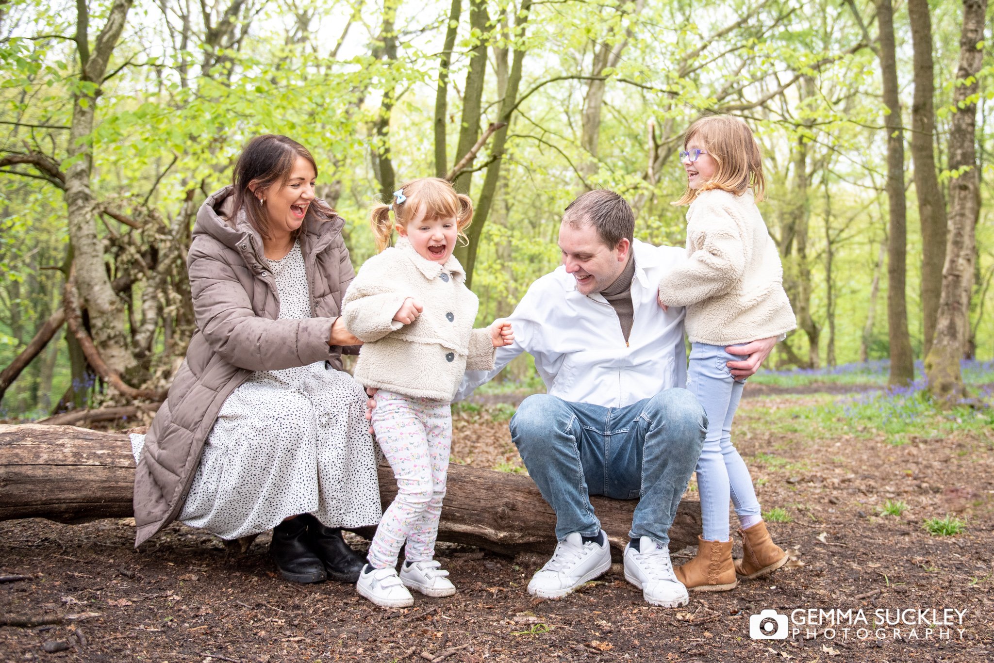 parents with their children sat on a log in shipley glen