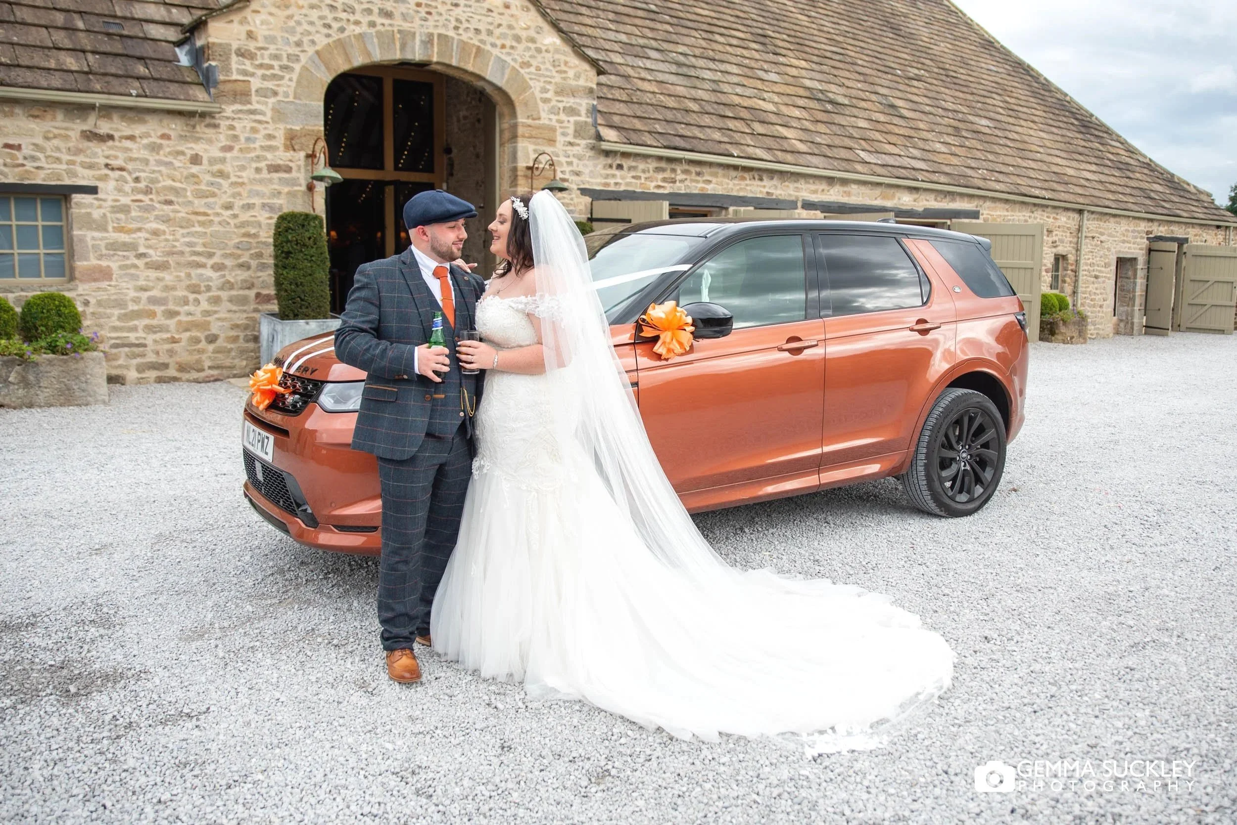 bride and groom with the wedding car outside the tithe barn