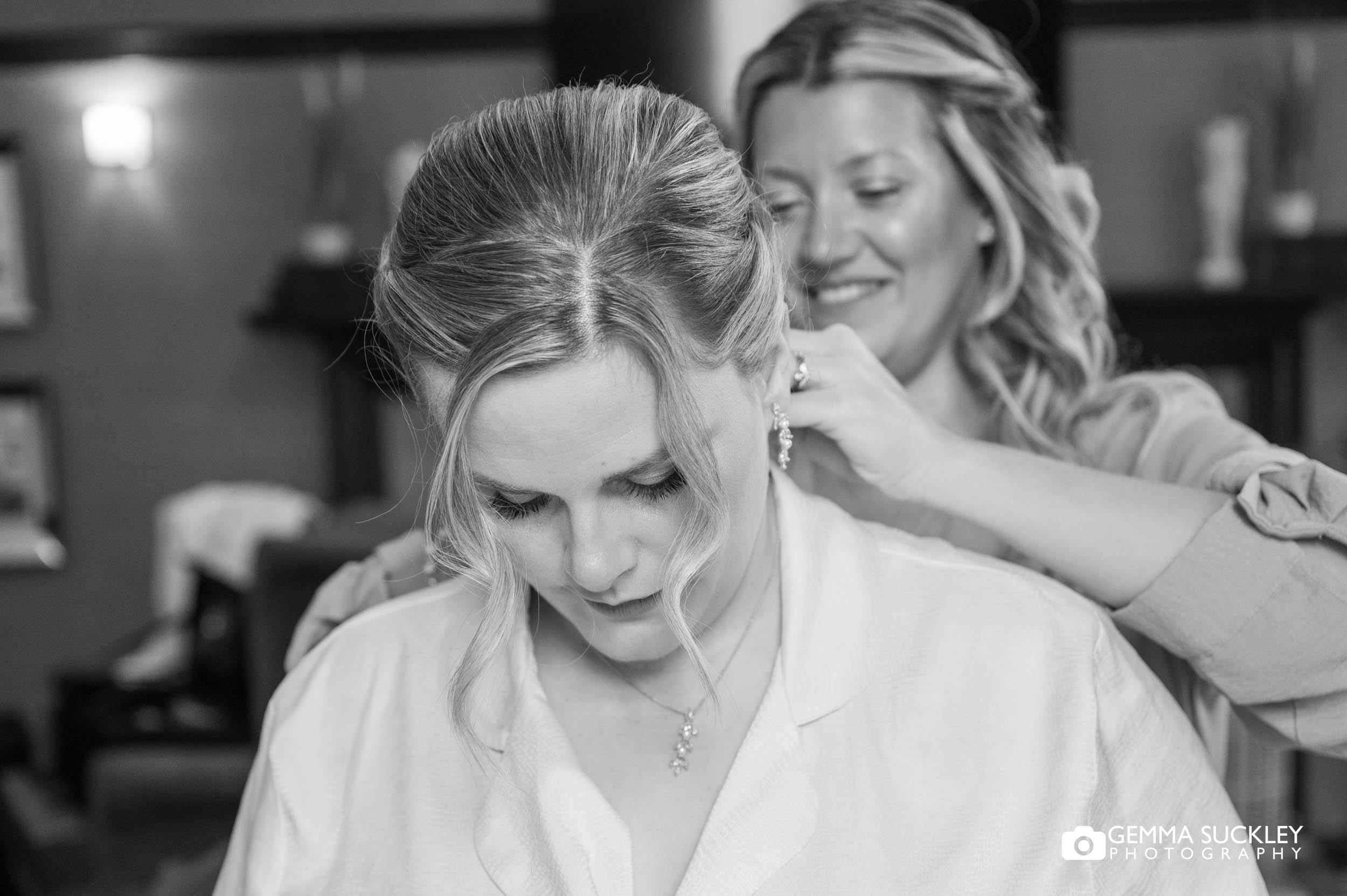 bridesmaid putting on the bride necklace at the falcon manor