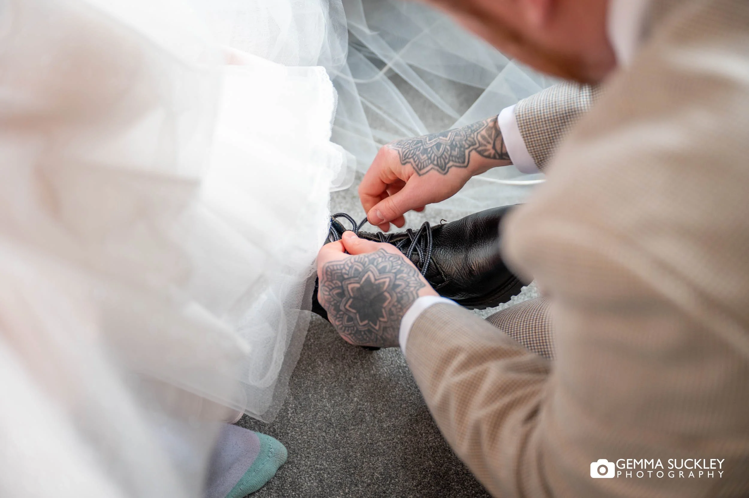 brides brother helping the bride tie her wedding shoes