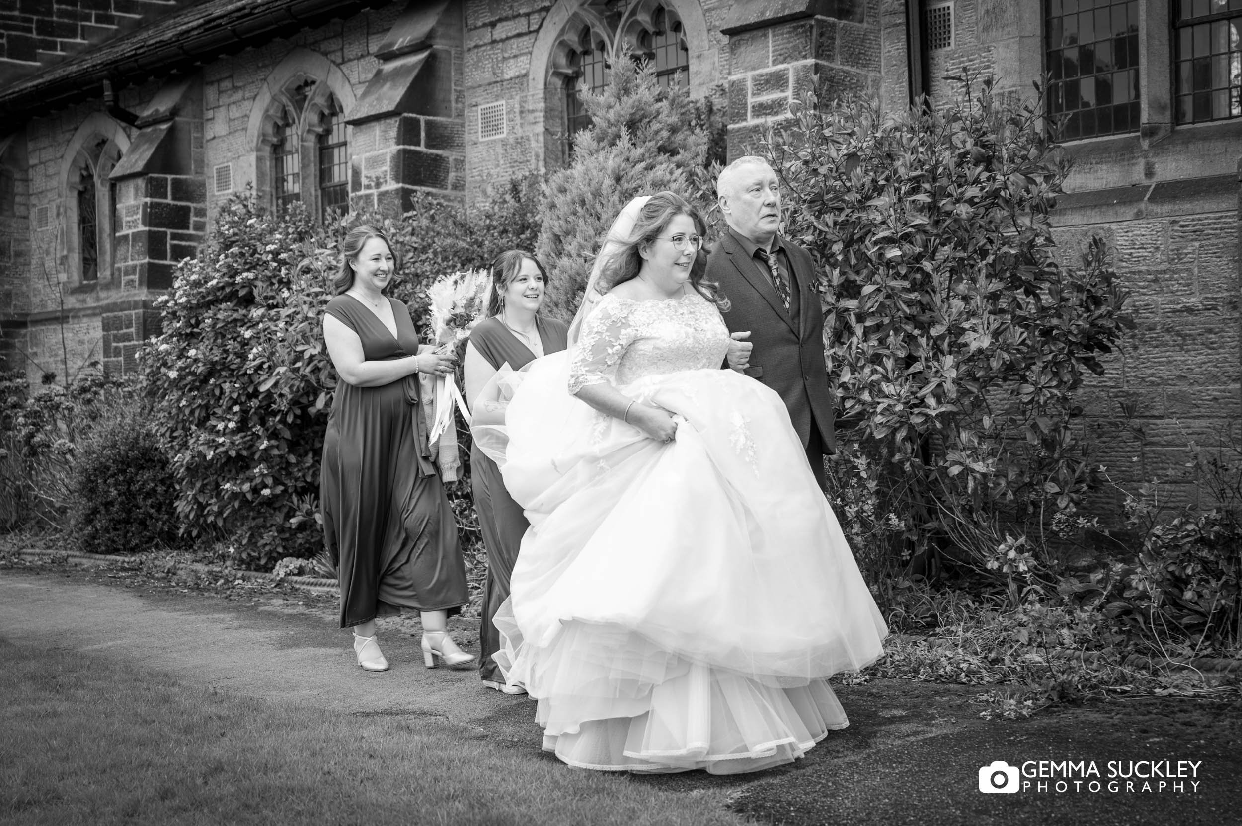 father and bridesmaids walking the bride to church in ilkley