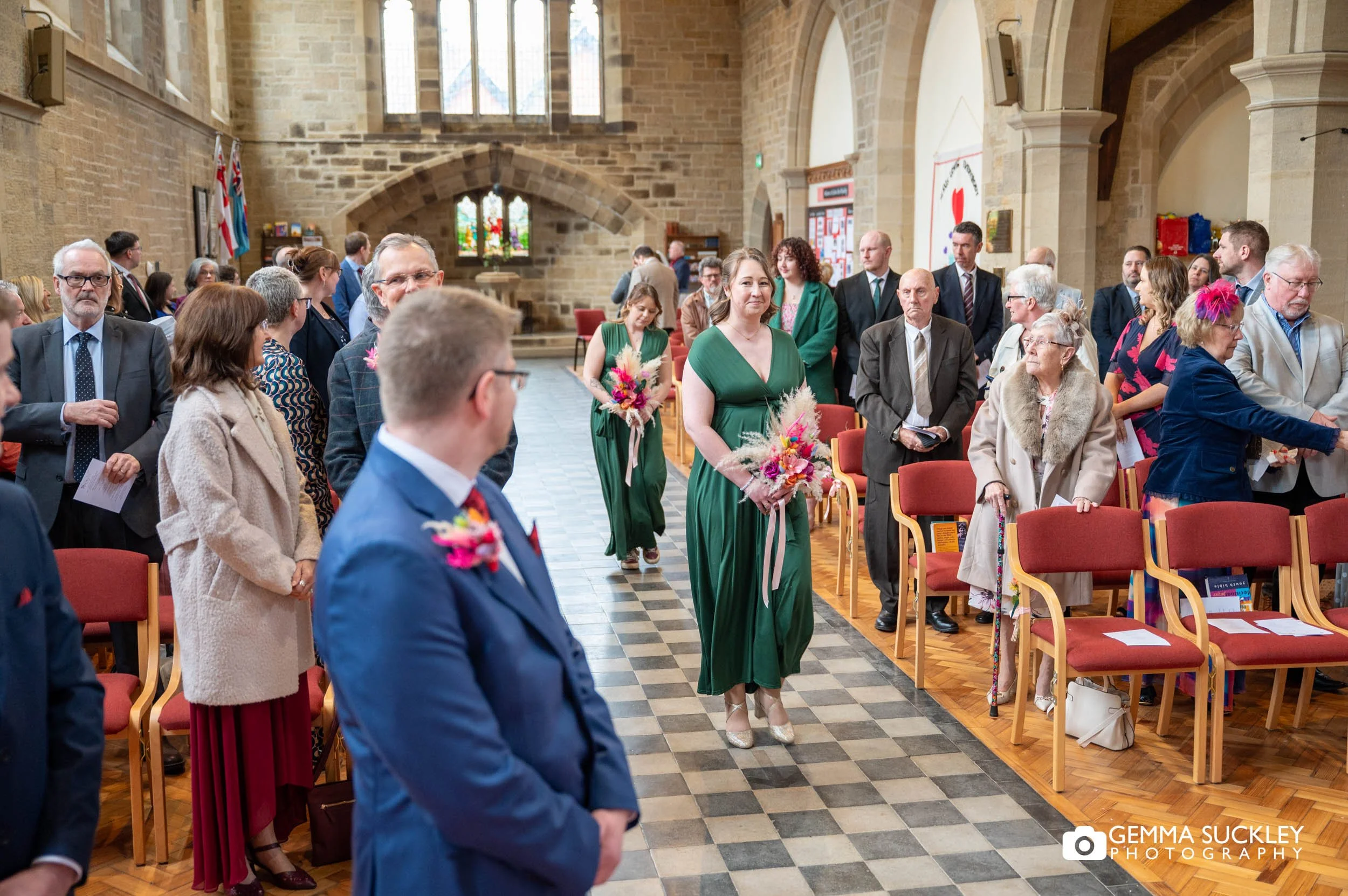 groom turning to see the bridesmaids walking down the aisle 
