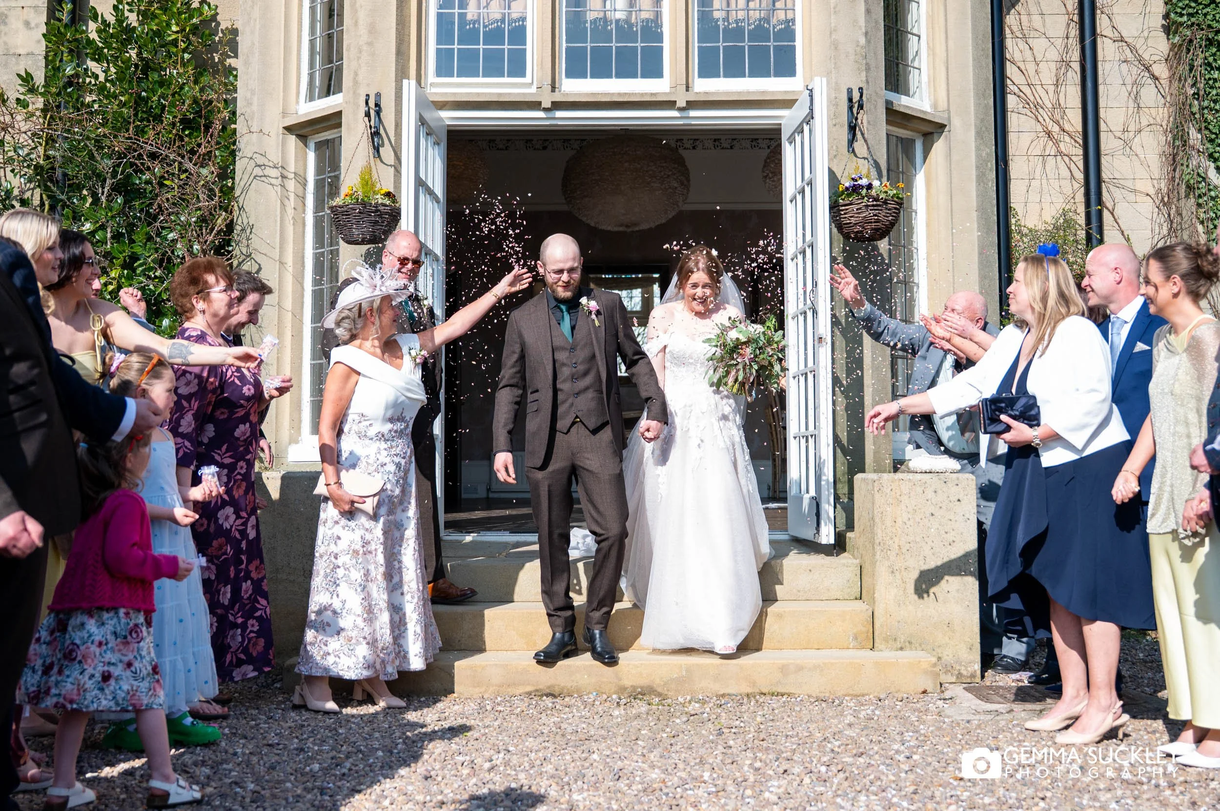 Wedding guests throwing confetti over the couple at Falcon Manor