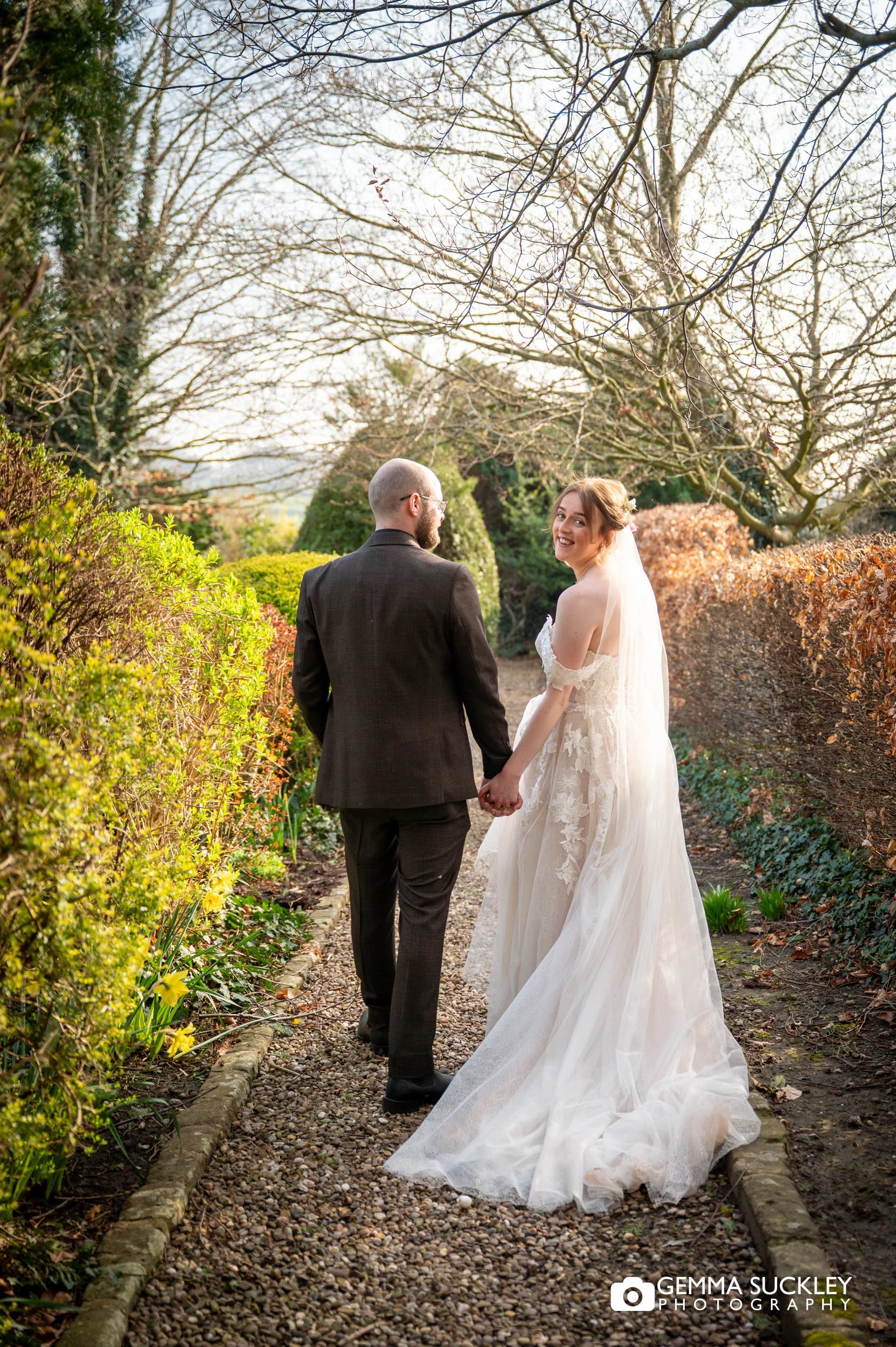 Bride and groom walking together in Falcon Manor grounds at golden hour