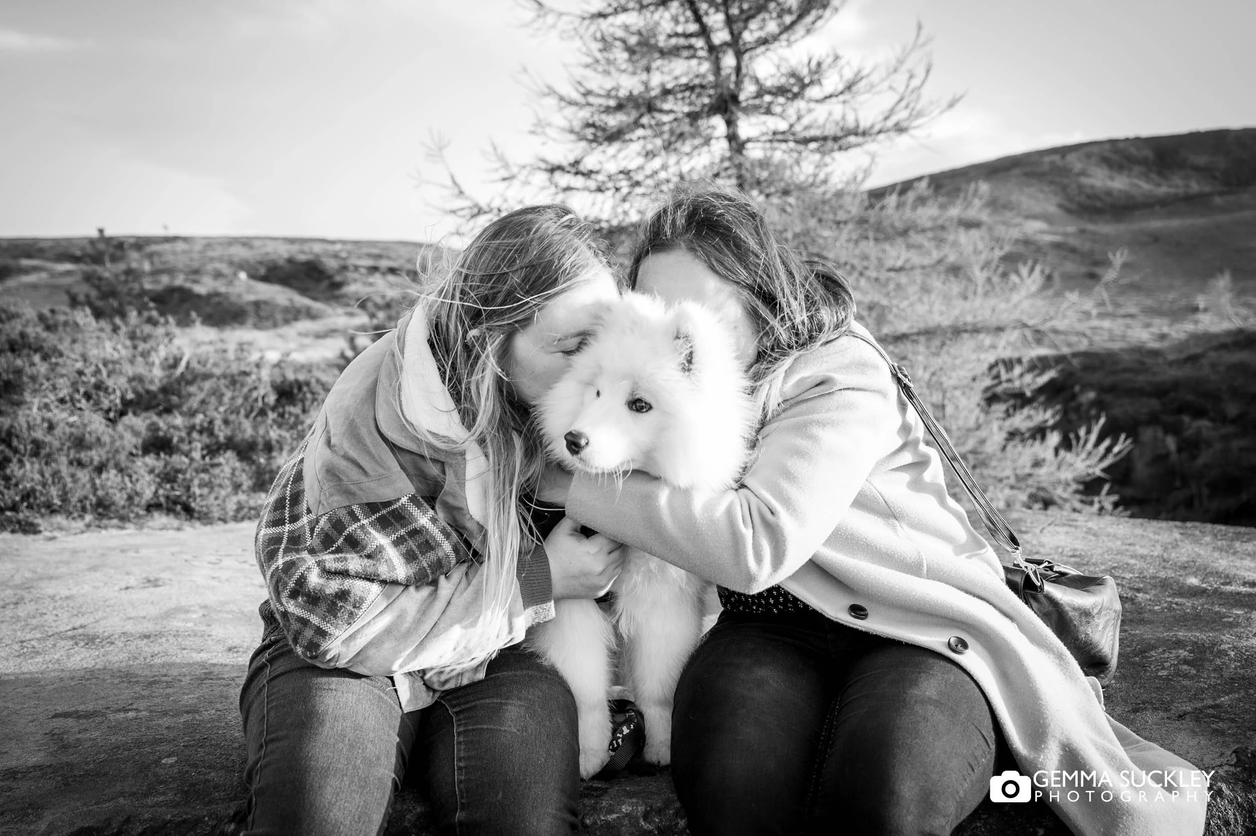 Couple cuddling their puppy during a relaxed pre-wedding shoot on Ilkley Moor