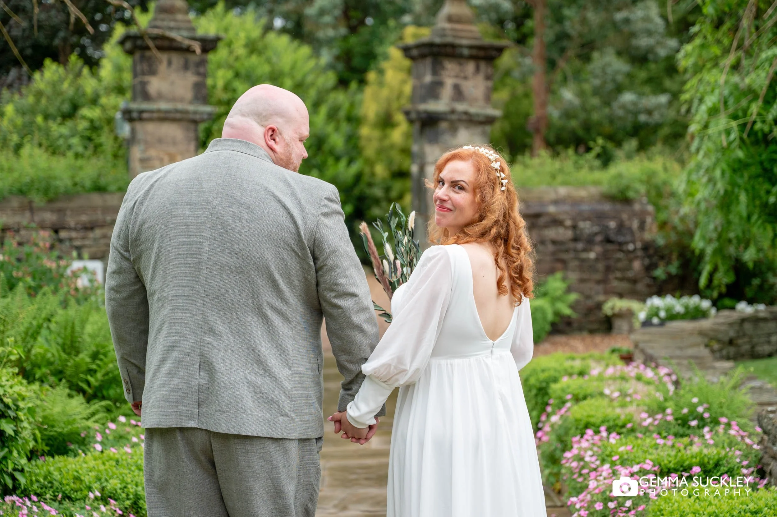 Bride and groom walking together in the gardens between rain showers