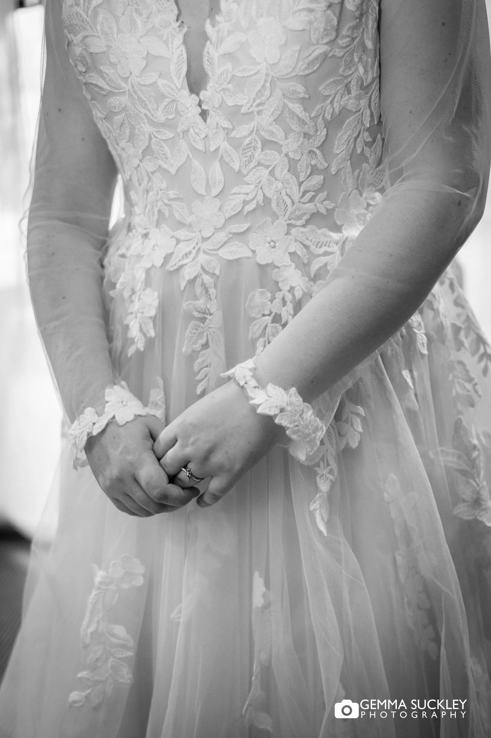 Close-up of bridal hands and wedding dress detail