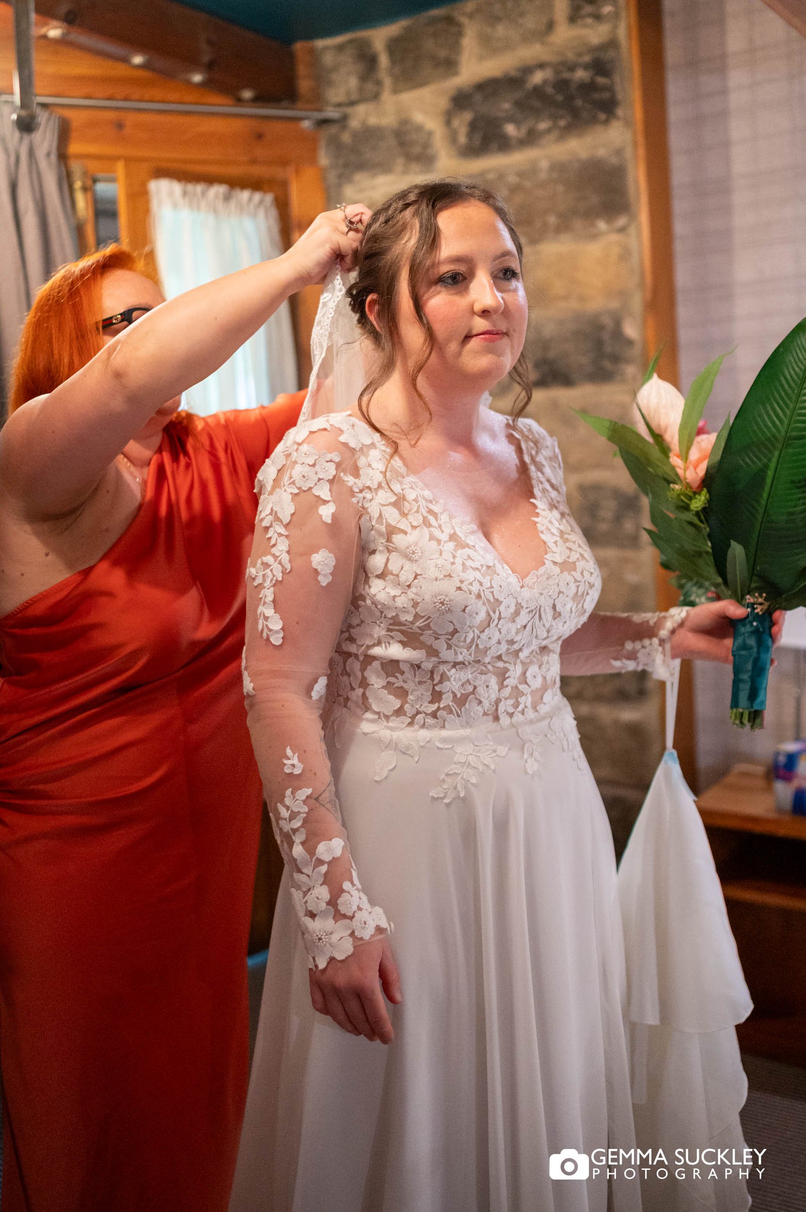 Bridesmaid helping the bride with final touches before the ceremony